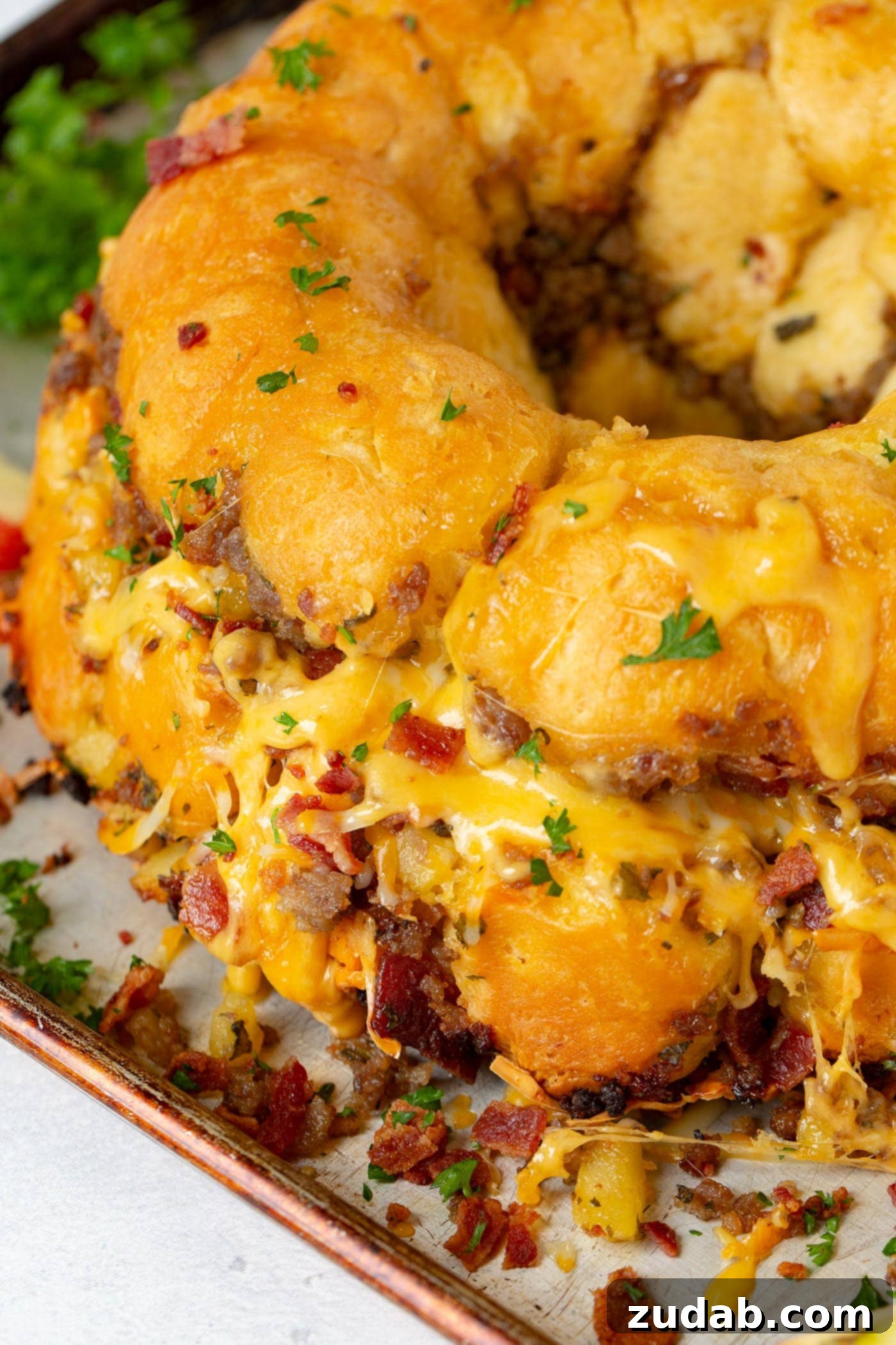 Breakfast Sausage and Apple Cheesy Pull Apart A close-up of baked sausage pull apart bread, generously covered in melted cheddar cheese. You can clearly see delicious chunks of breakfast sausage and crispy bacon embedded within the golden-brown bread, inviting you to pull a piece.