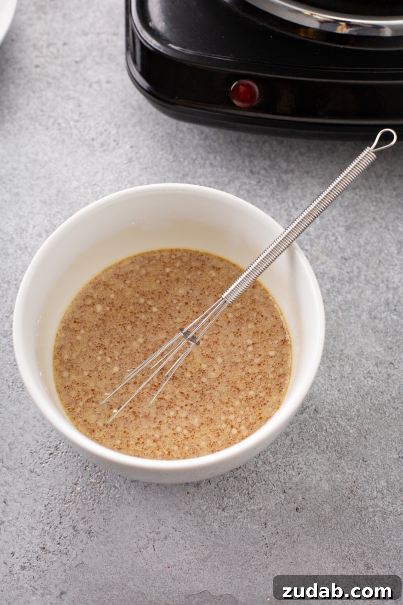 Easy Egg Drop Soup A bowl with a whisk and ingredients for the soup.