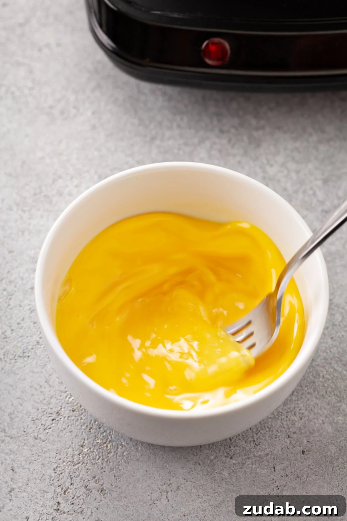 Easy Egg Drop Soup A bowl with whipped eggs and a fork.