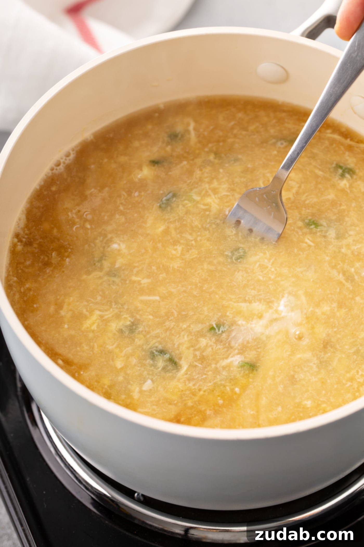 Easy Egg Drop Soup A bowl of egg drop soup with a fork resting in it.