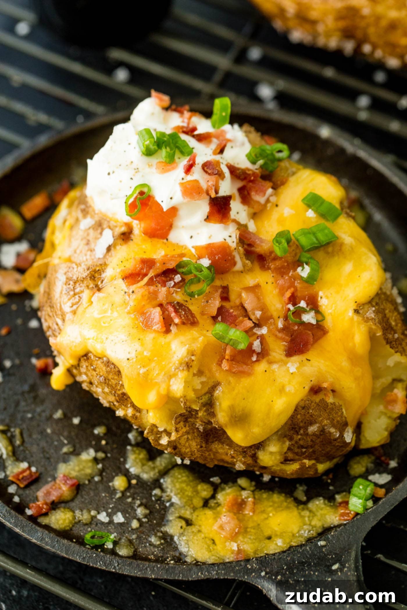 a loaded baked potato with cheese, sour cream, butter, bacon and green onions