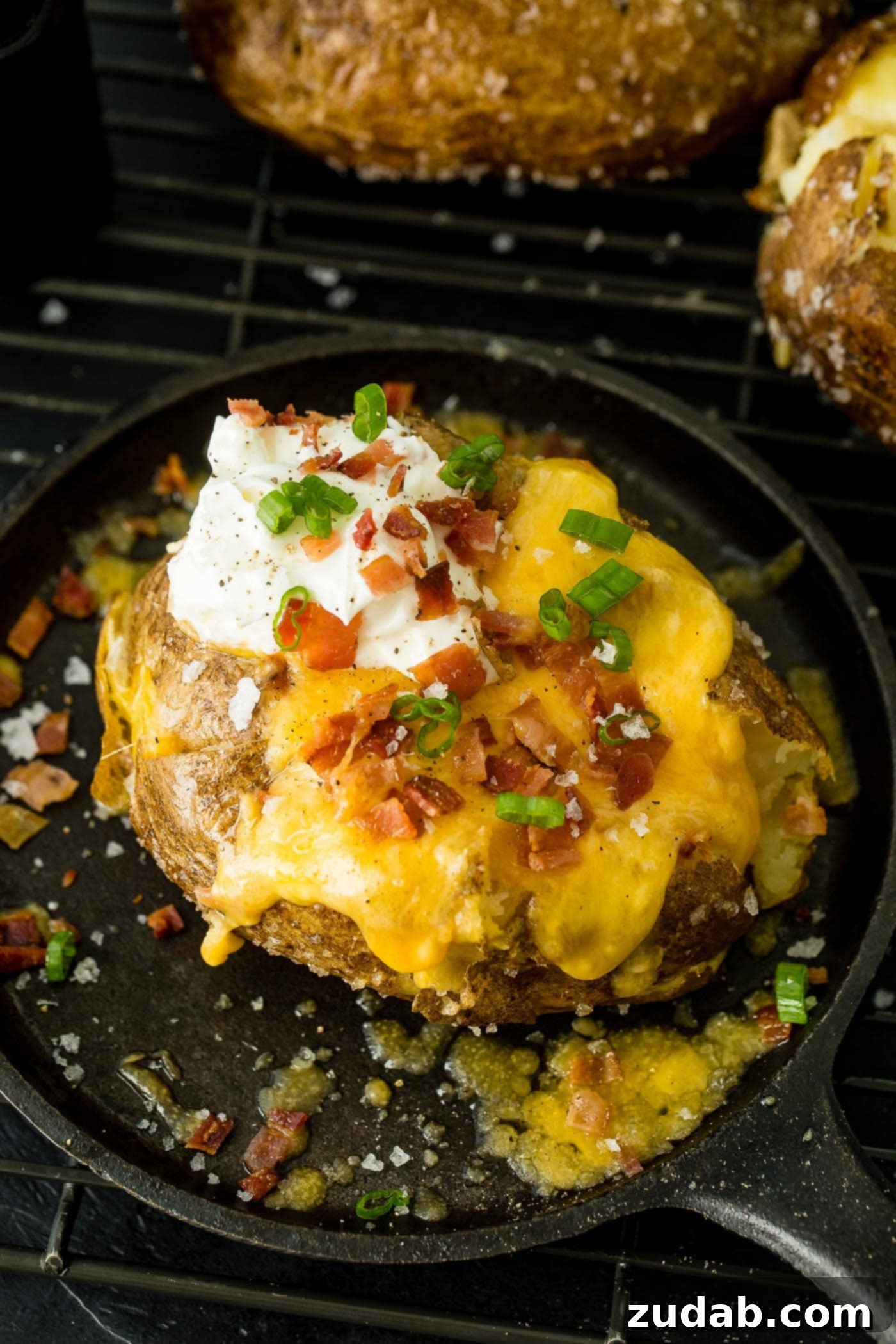 a loaded baked potato with cheese, sour cream, butter, bacon and green onions
