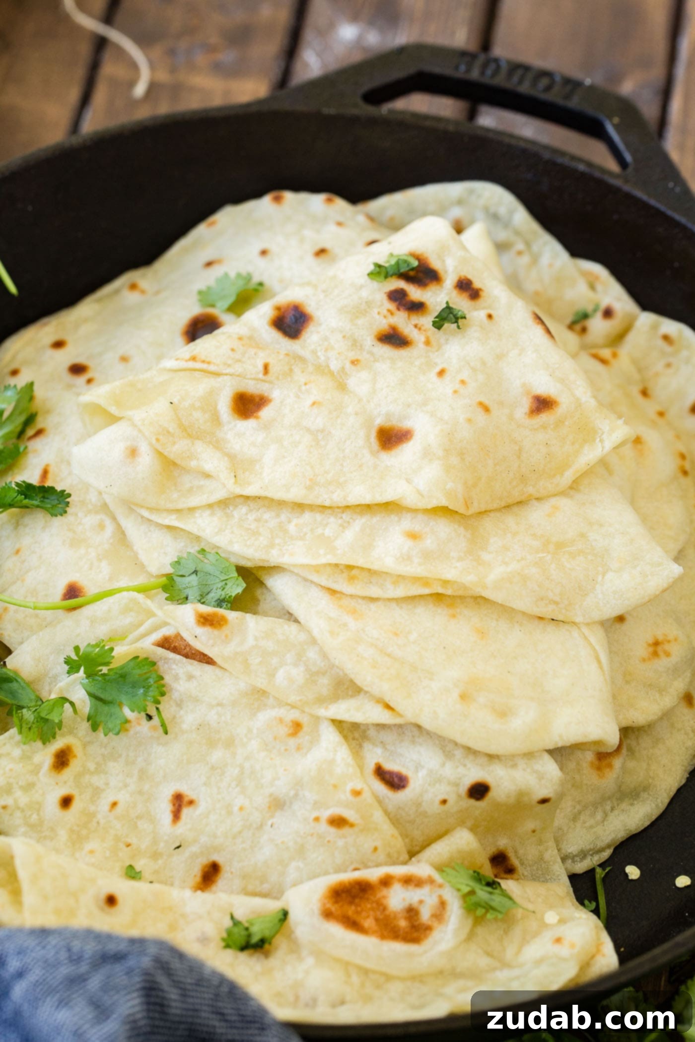 A photo of a stack of cooked mexican wraps in a cast iron skillet with the top few tortillas folded in quarters.