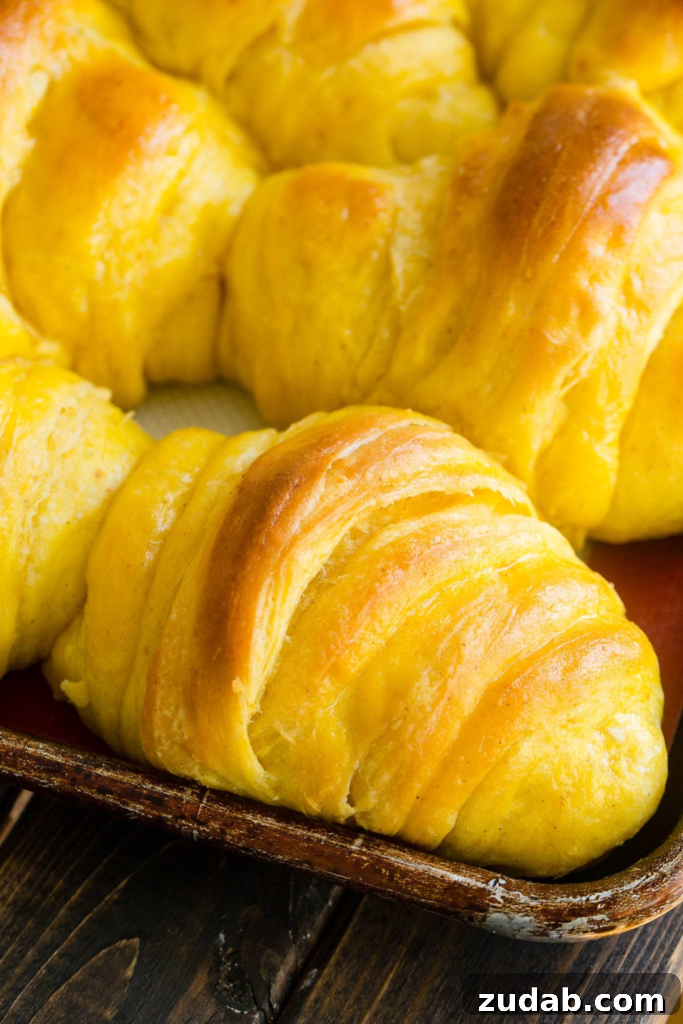 Pillowy Pumpkin Dinner Rolls 10 Close-up of a warm pumpkin dinner roll being brushed with melted butter, emphasizing its irresistible softness