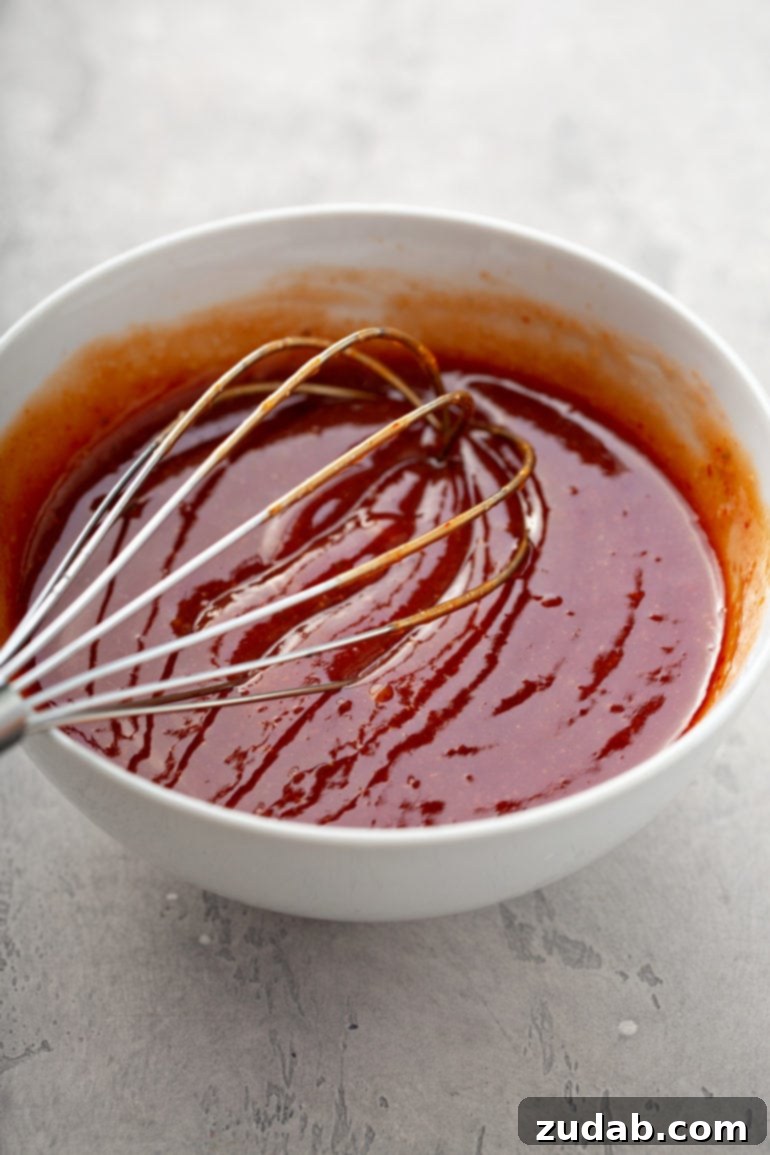 Our Favorite Classic Meatloaf 4 A vibrant red meatloaf glaze, a perfect blend of ketchup, chili sauce, brown sugar, and Worcestershire, being whisked in a bowl, ready to transform the classic meatloaf.