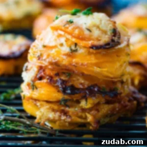 A stack of thinly sliced sweet potatoes layered with gruyere and parmesan cheese and topped with fresh thyme.