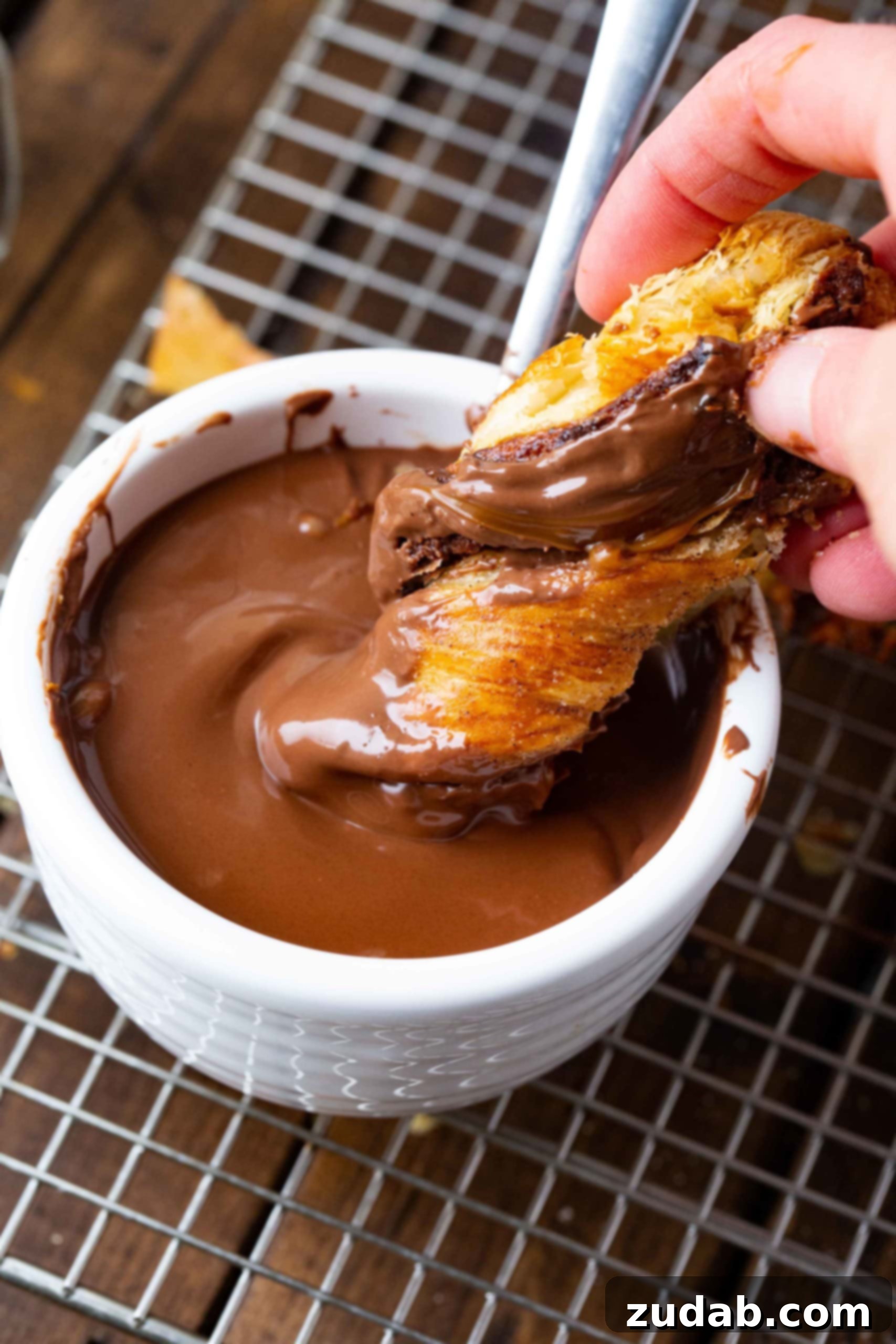 Nutella Dulce de Leche Christmas Tree A warm, twisted puff pastry dessert being dipped into a luscious bowl of melted Nutella, highlighting the tempting layers.