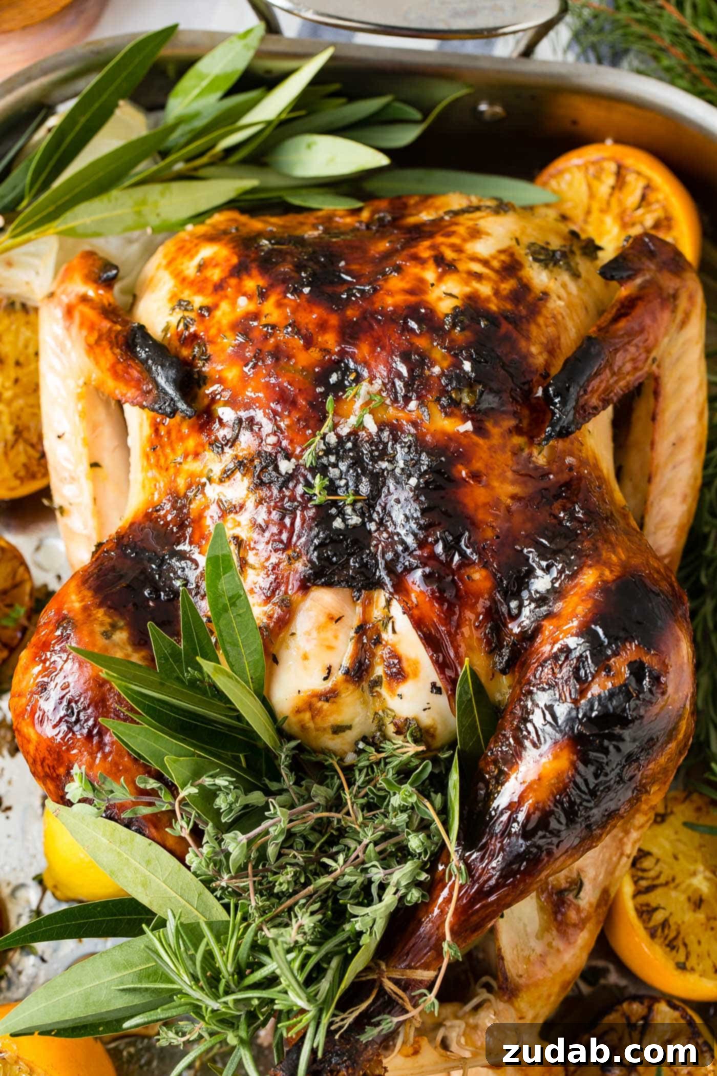The Best Oven Roasted Thanksgiving Turkey Ever A photo of a whole roasted turkey on a platter surrounded by roasted lemon halves and bunches of fresh herbs.