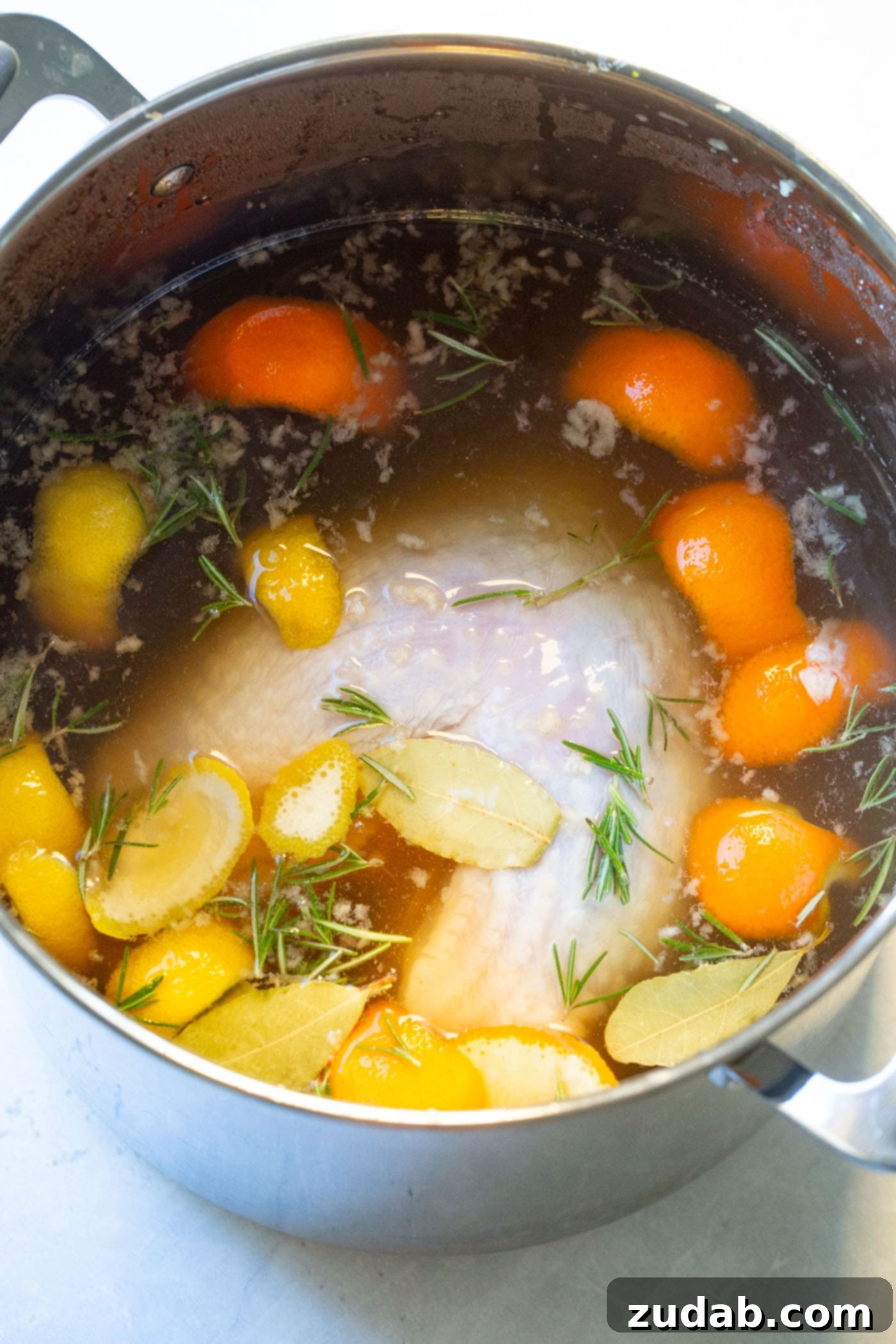 The Best Oven Roasted Thanksgiving Turkey Ever A photo of a whole turkey submerged in brine in a stock pot.