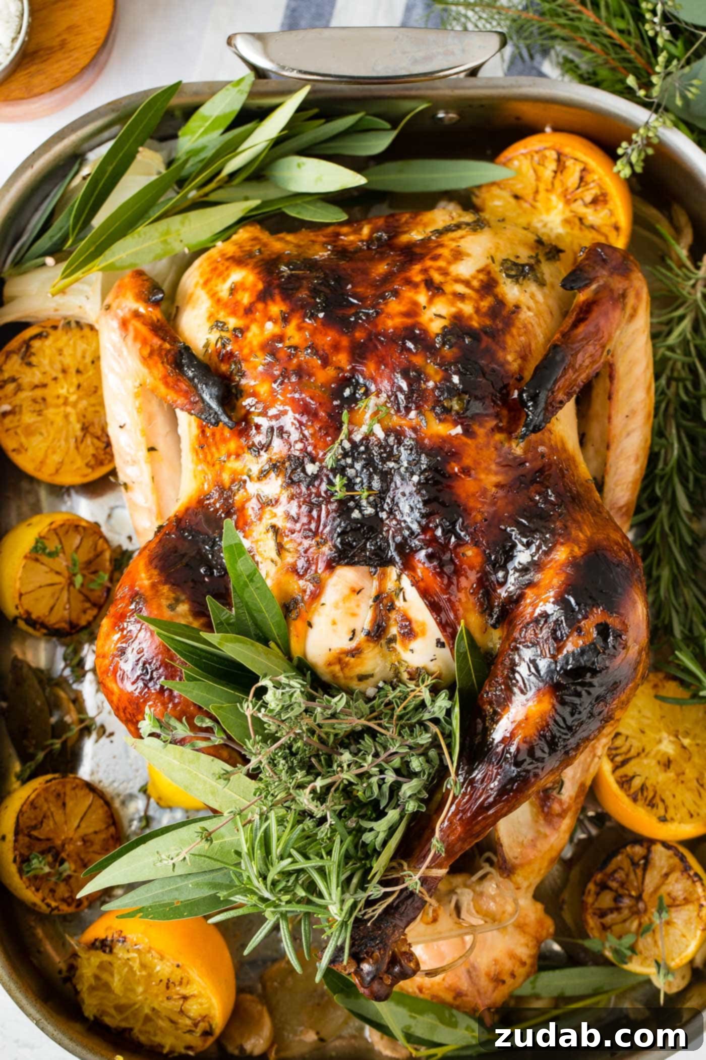 The Best Oven Roasted Thanksgiving Turkey Ever A photo of a whole roasted turkey on a platter surrounded by roasted lemon halves and bunches of fresh herbs.