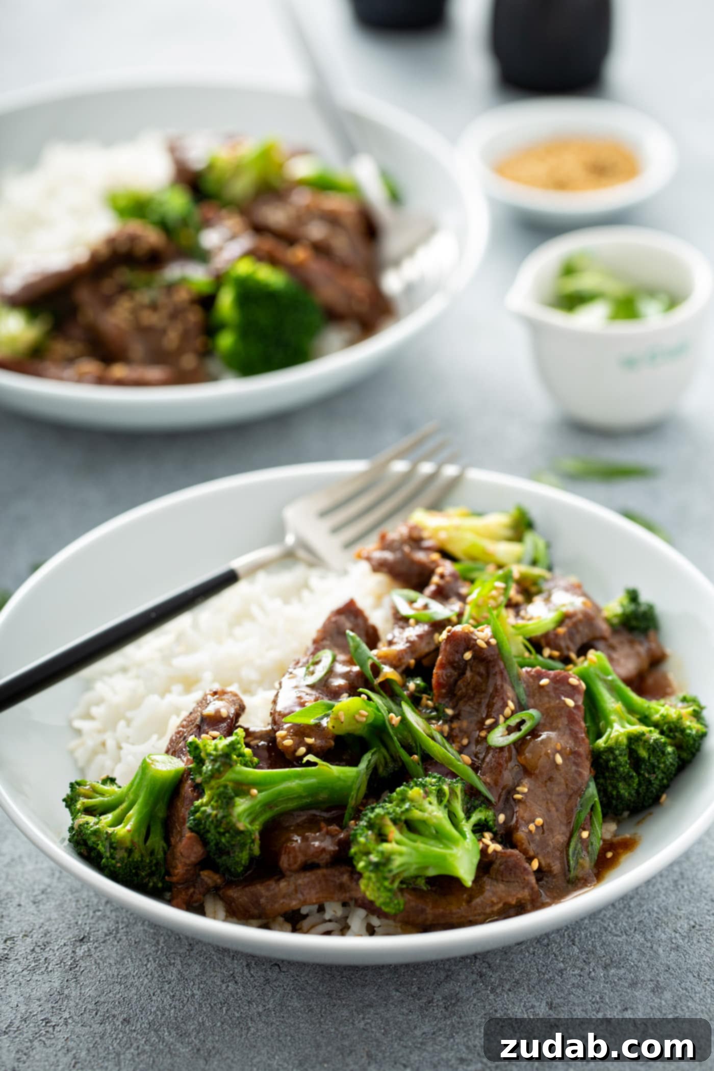 Instant Pot Beef and Broccoli A photo of a bowl of beef and broccoli with another bowl of the same dish in the background.
