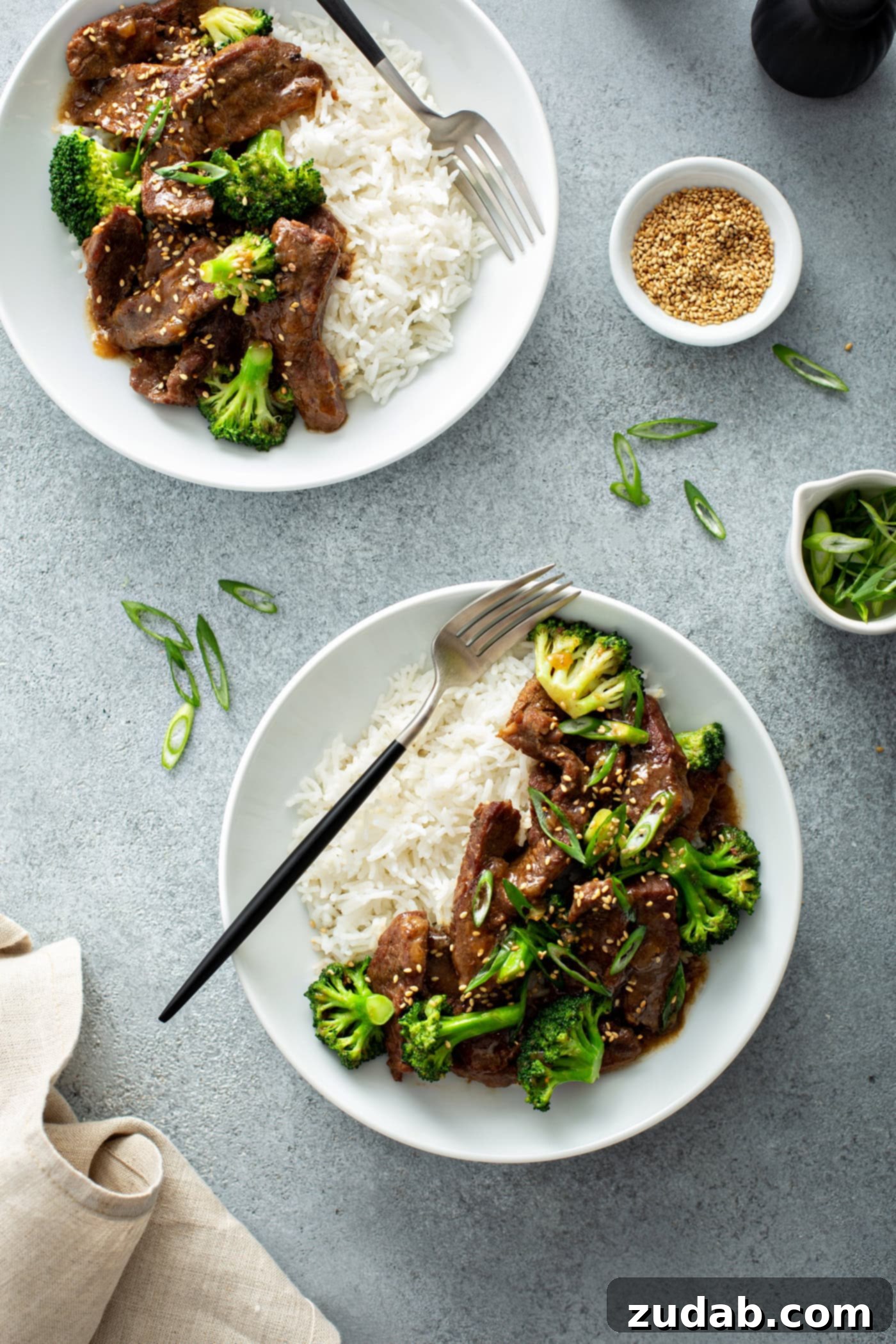 Instant Pot Beef and Broccoli A photo of two bowls of beef and broccoli with a side of white rice.