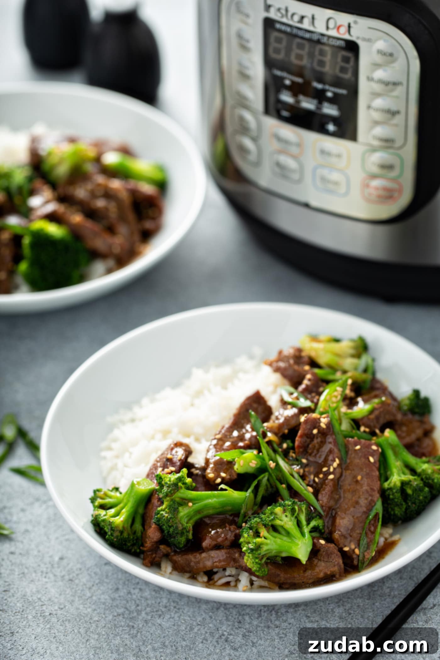 Instant Pot Beef and Broccoli A photo of a white bowl full of beef and broccoli with a side of white rice.