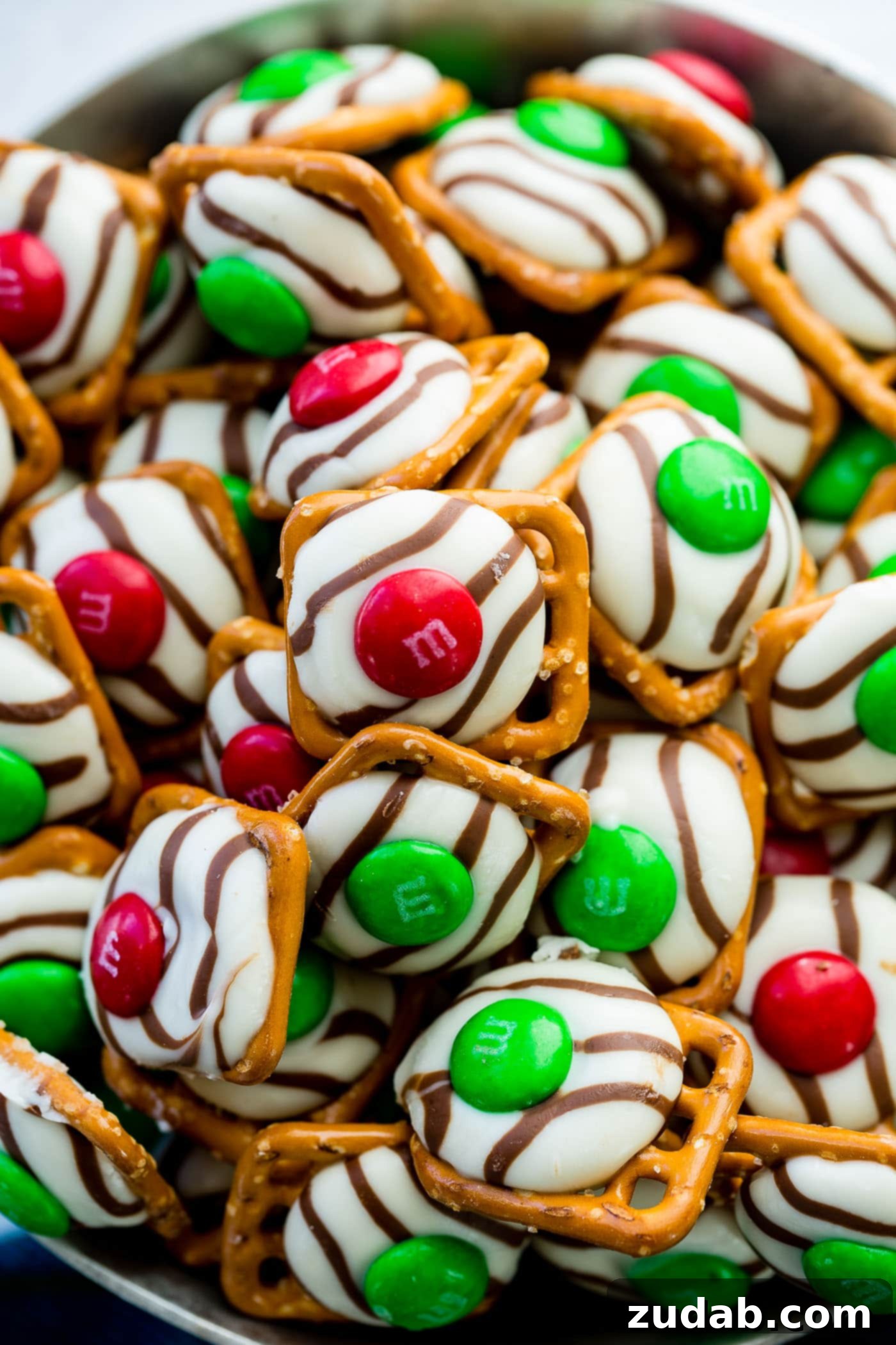 Addicting Christmas M&M Pretzel Hugs A bowl of festive Christmas M&M Pretzel Hugs with red and green candies