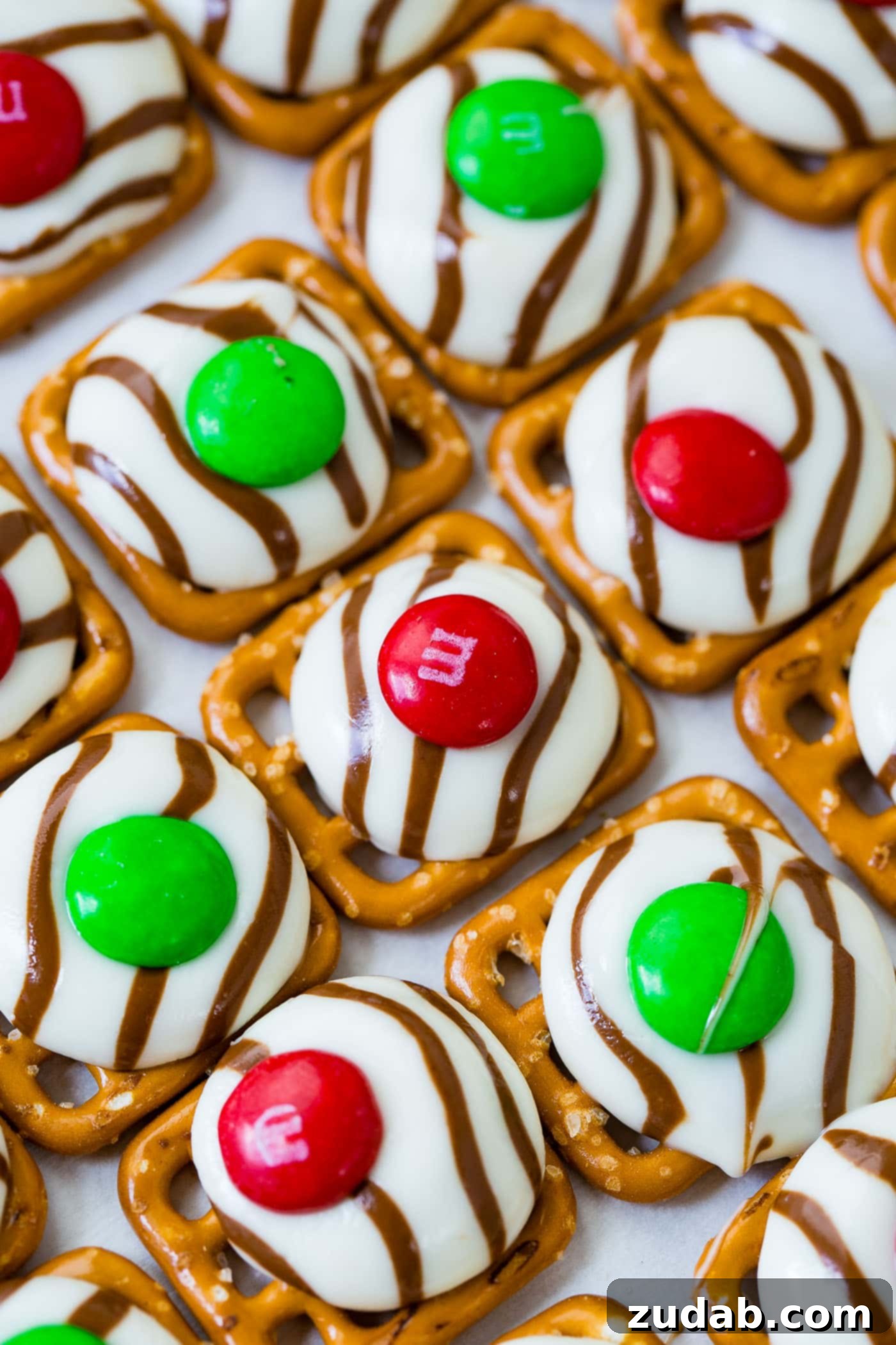 Addicting Christmas M&M Pretzel Hugs A close-up of Christmas M&M Pretzel Hugs arranged on a cookie sheet