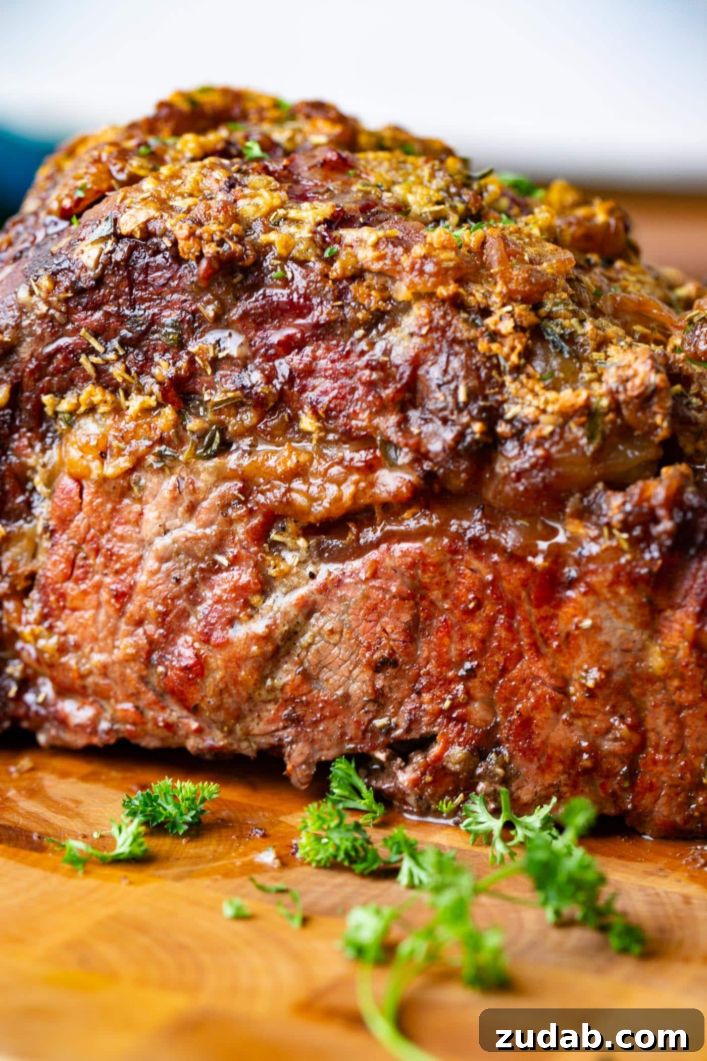 Traeger Smoked Prime Rib A photo of a whole juicy smoked prime rib sitting on a cutting board garnished with fresh chopped parsley.