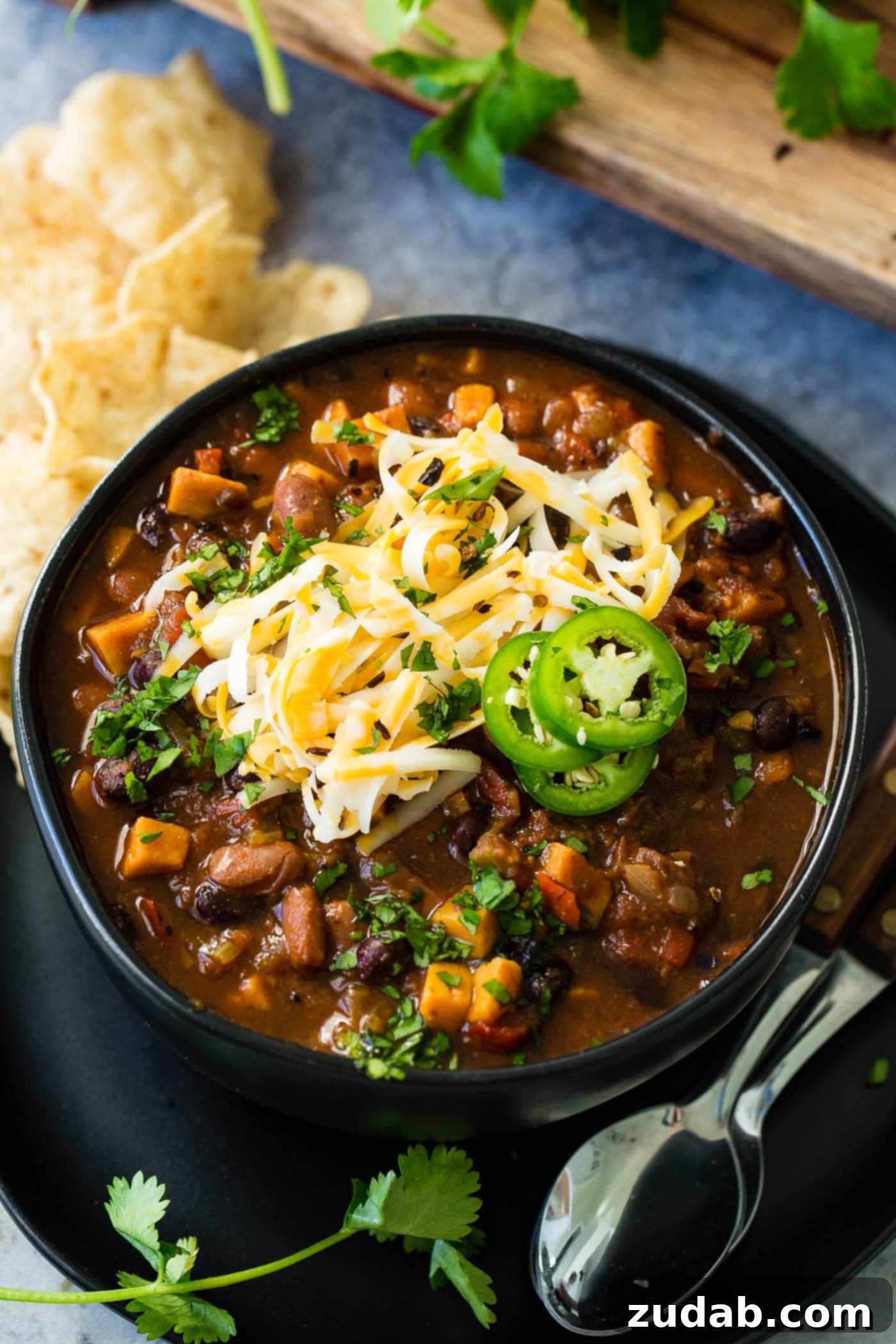 Instant Pot Vegetarian Chili A close-up photo of a bowl of hearty instant pot vegetarian chili, rich with beans and vegetables, topped with shredded cheese and sliced jalapeno.