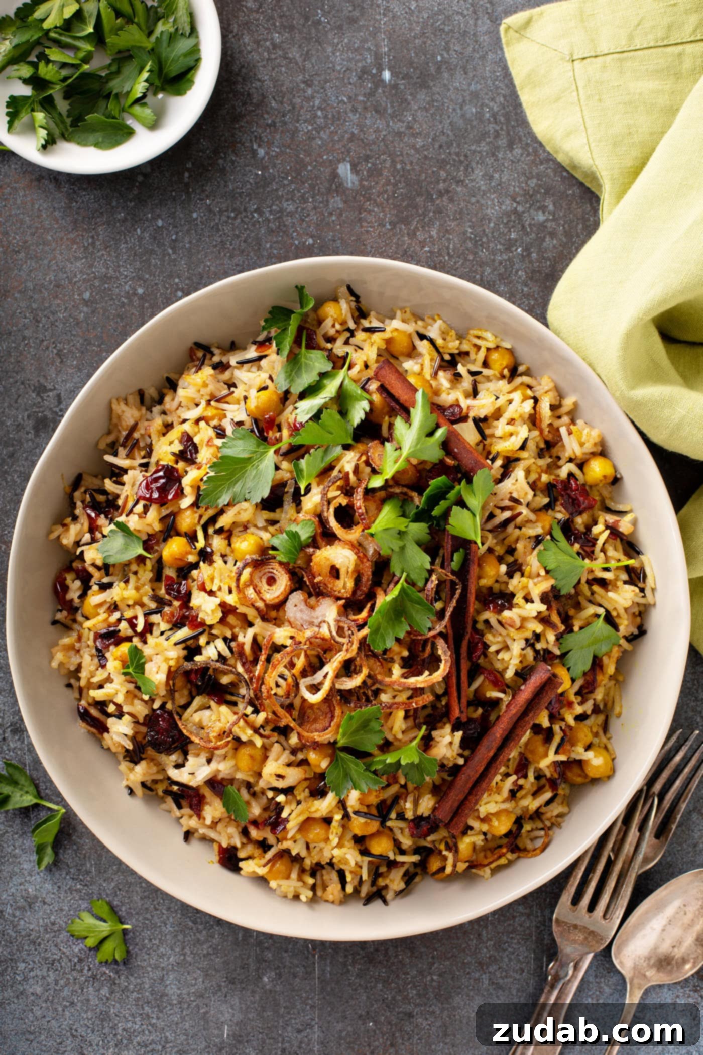 Wild Rice and Chickpeas with Crispy Shallots A photo of a large white serving bowl full of Jerusalem wild rice topped with spiced chickpeas, fried shallots and chopped fresh parsley.