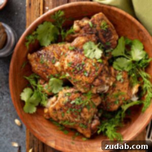 Jerusalem-Style Herbed Chicken Thighs 3 A bowl filled with five Jerusalem Herbed Chicken Thighs topped with cilantro leaves and dill leaves