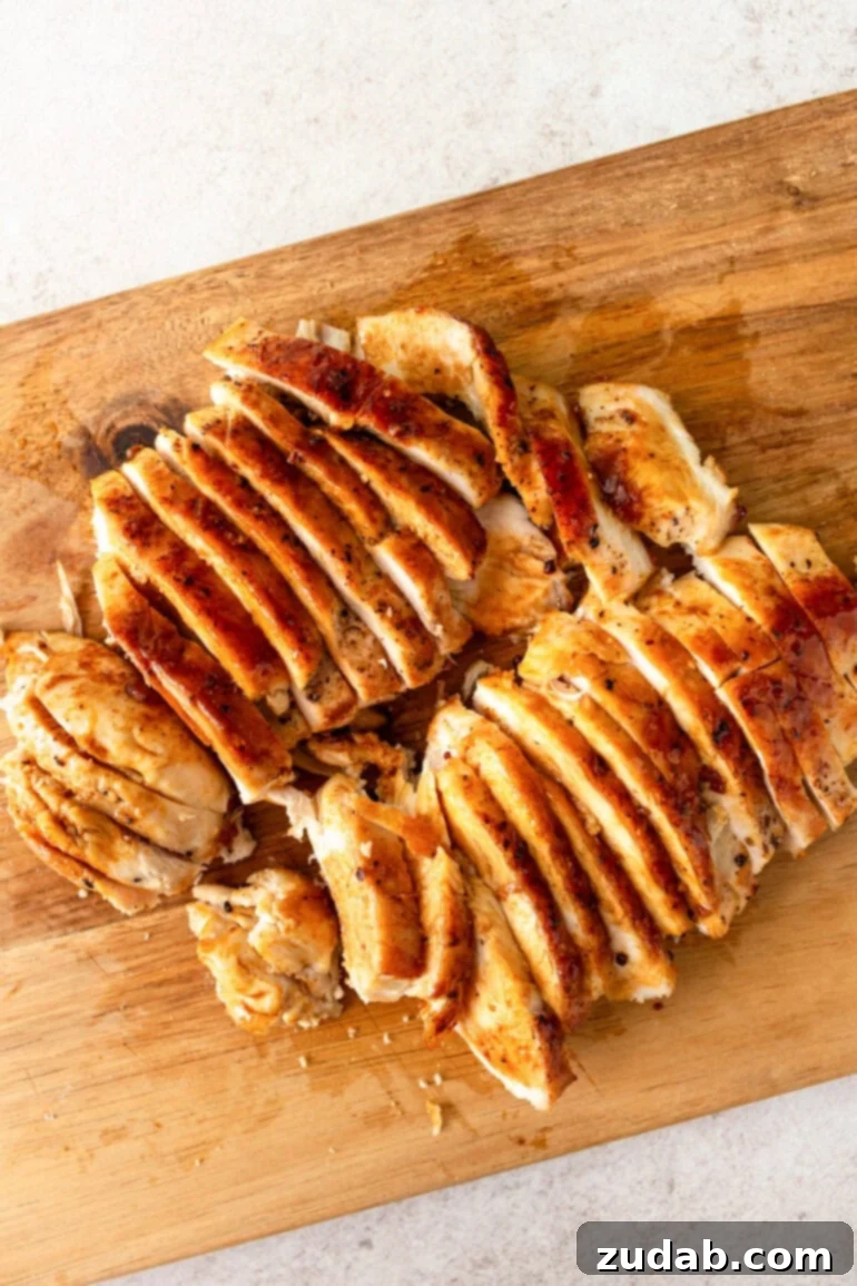 Lemon Basil Chicken Pasta 3 a photo of golden cooked chicken breasts sliced and sitting on a wooden cutting board.
