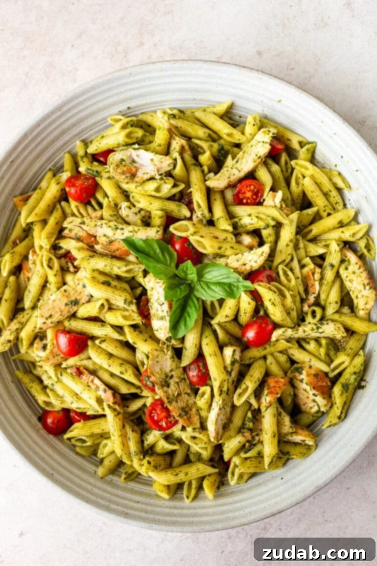 Lemon Basil Chicken Pasta 9 a photo of a large white serving bowl full of cooked penne pasta tossed with a honey lemon basil sauce, halved cherry tomatoes, and chicken strips
