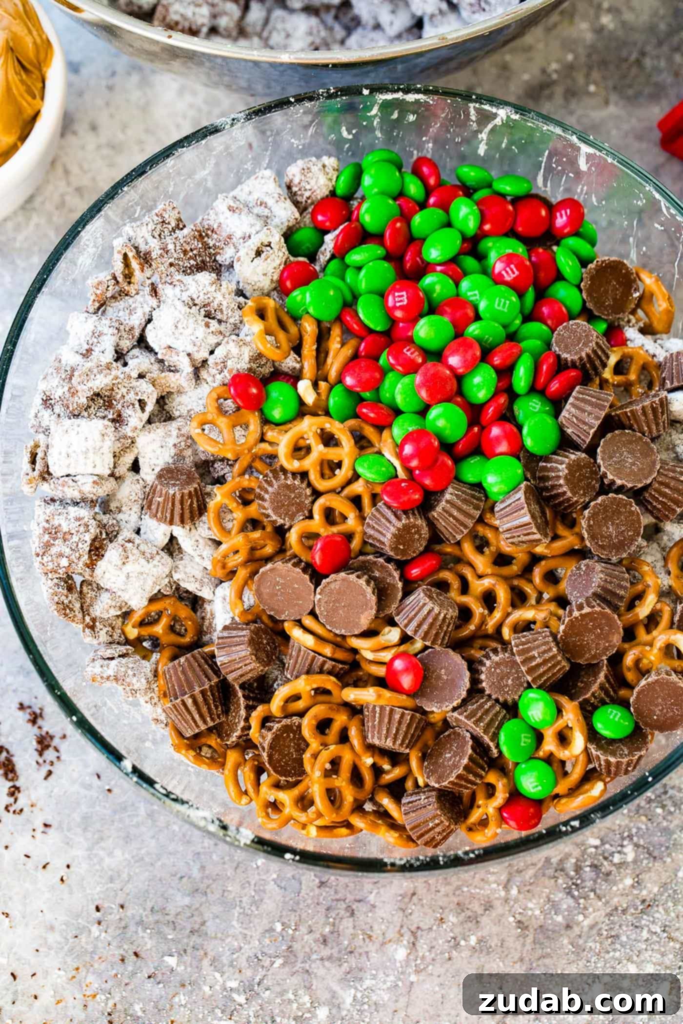 Reindeer Muddy Buddies Christmas Snack Mix An inviting close-up of the Christmas snack mix, emphasizing the rich chocolate and peanut butter flavors from the muddy buddies and peanut butter cups, a perfect indulgence.