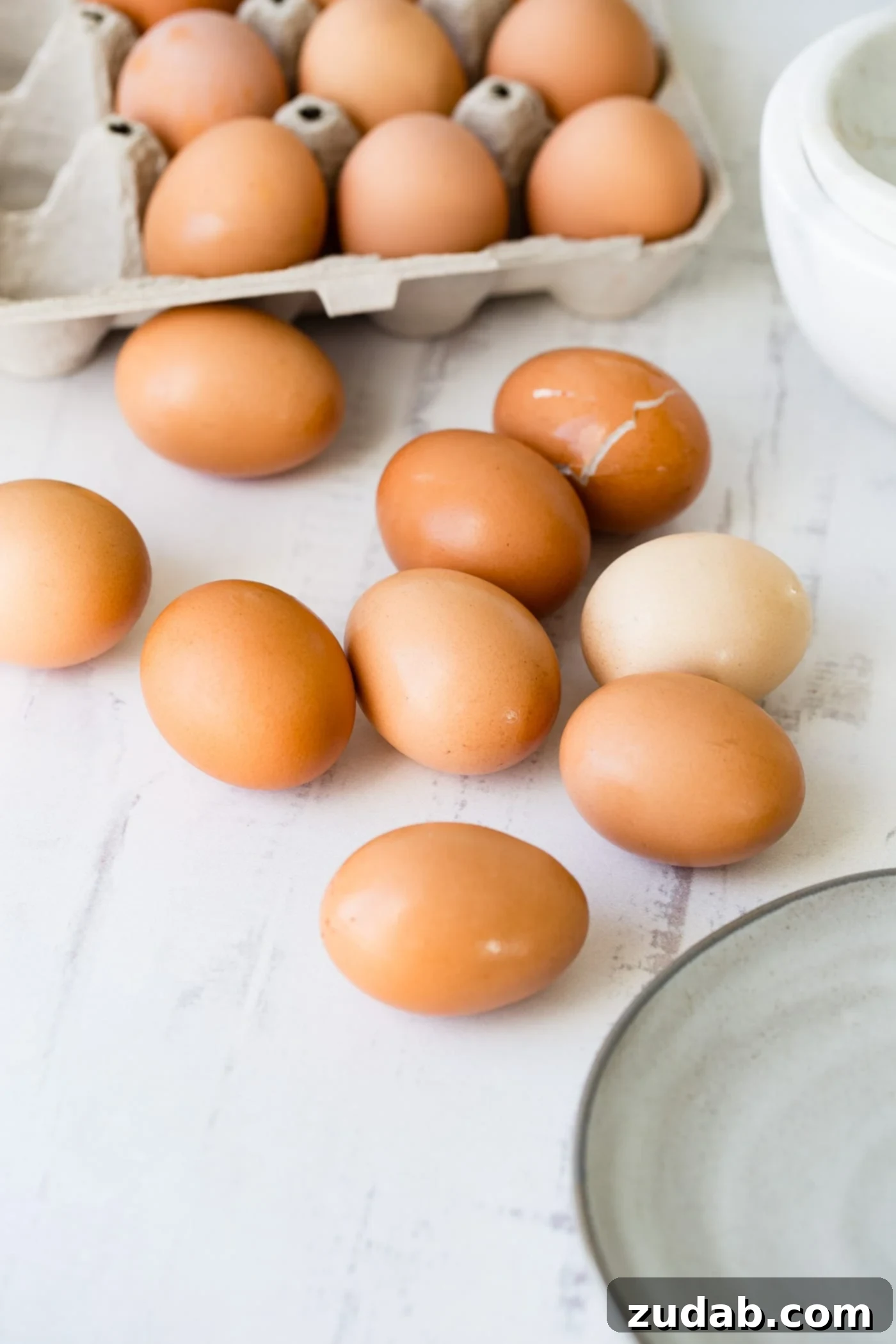 How to Make Perfect Hard Boiled Eggs Nine fresh brown eggs resting on a kitchen counter with an open carton of brown eggs in the background, ready for cooking.
