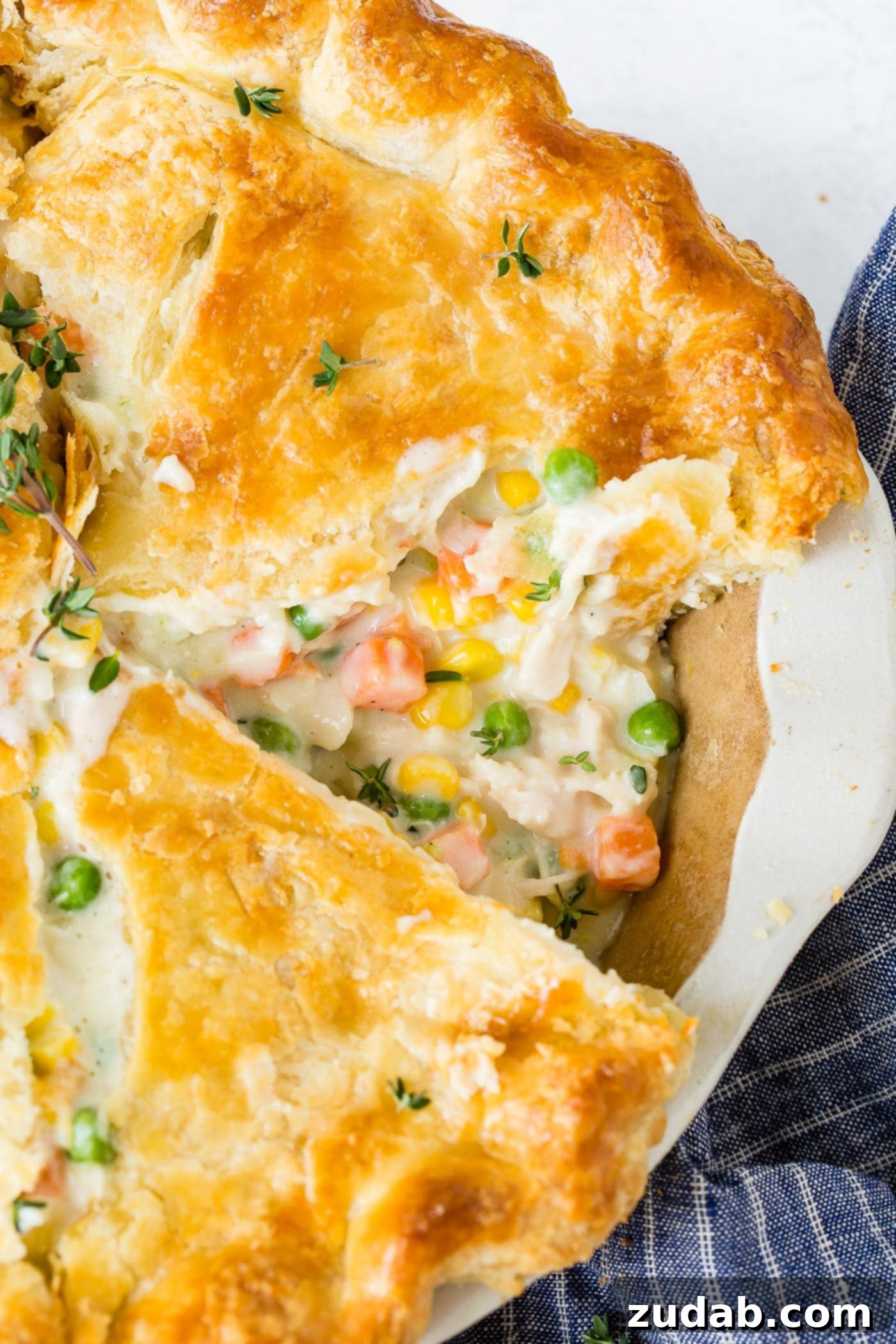 My Best Homemade Chicken Pot Pie Recipe A whole chicken pot pie with one piece cut showing the creamy sauce and carrots and peas and chicken in the filling.