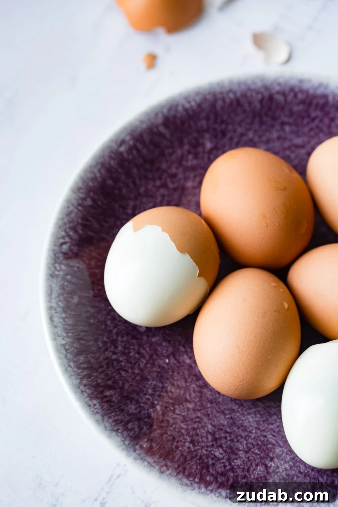 Instant Pot Hard Boiled Eggs A plate with 6 brown hard boiled eggs. On egg is peeled and another egg is partially peeled.