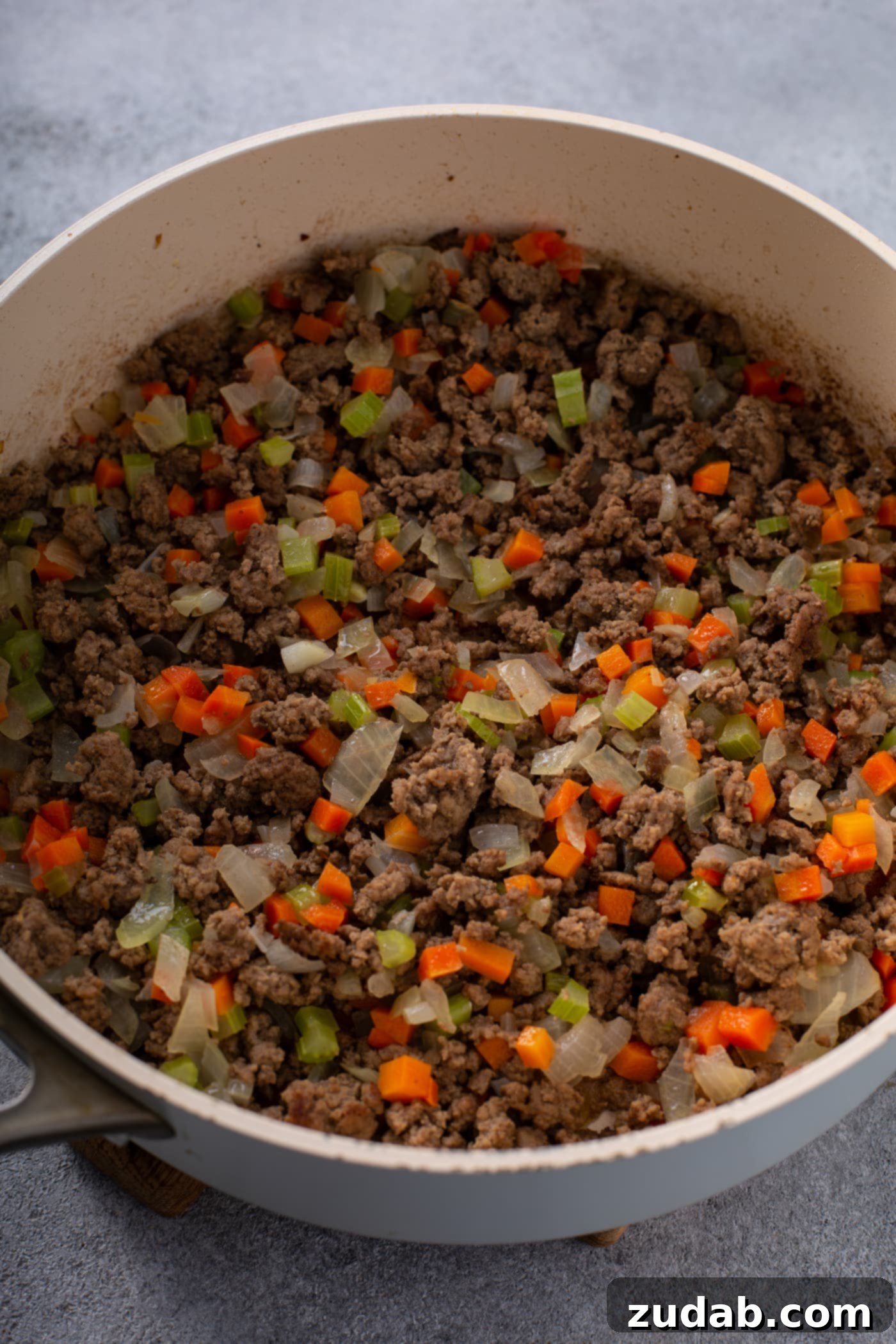 Classic Shepherd's Pie A casserole dish filled with browned ground beef, onions, peas, and carrots.