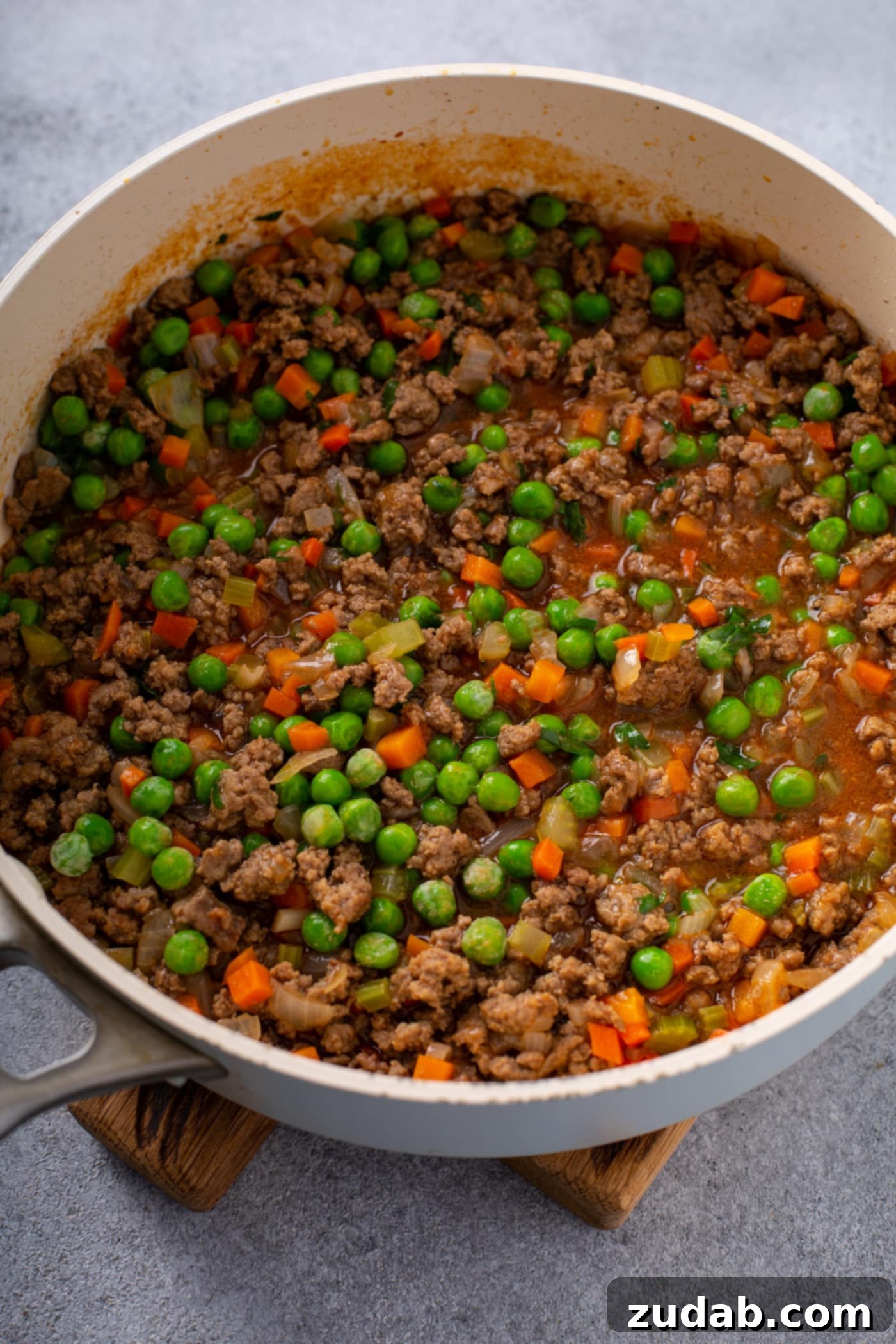 Classic Shepherd's Pie A casserole dish filled with browned ground beef, carrots, peas, onions and celery.