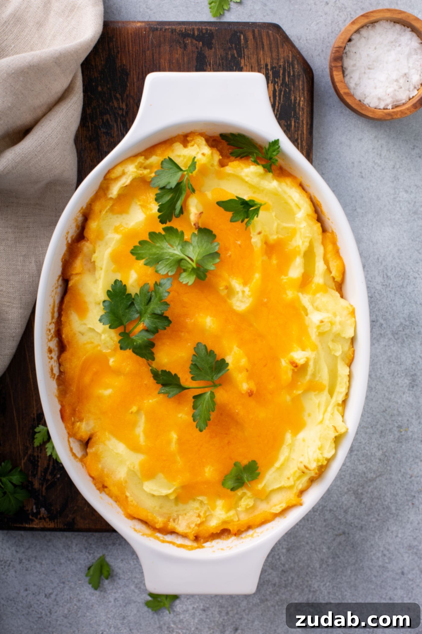 Classic Shepherd's Pie A casserole dish containing a baked shepherd's pie. It is topped with melted cheese and parsley leaves.