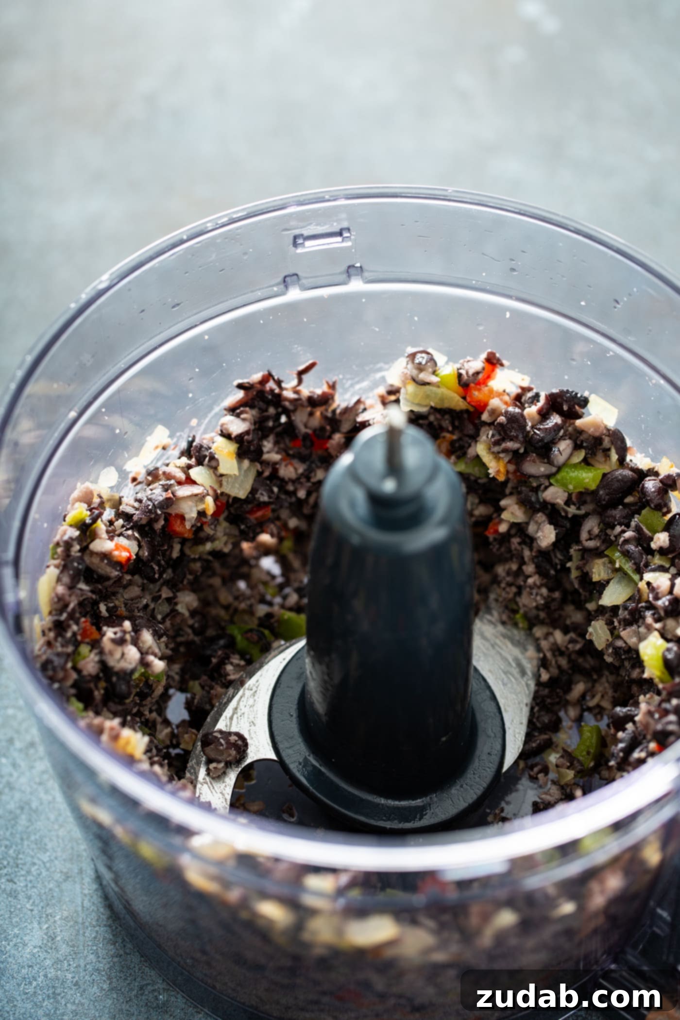 Your New Favorite Homemade Black Bean Burger 7 A food processor containing ground black beans and peppers, illustrating the mixing process for the burger patties.