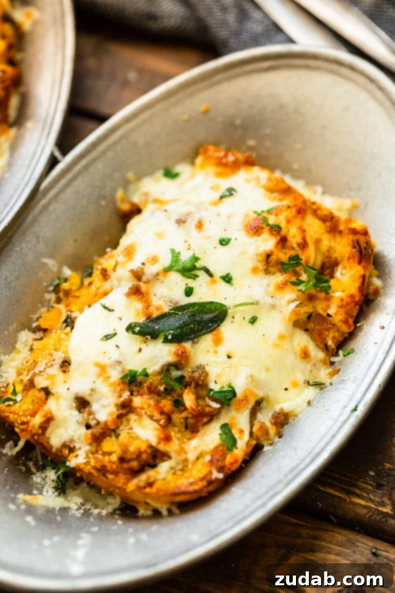 a photo of a large serving of butternut squash lasagna topped with melted cheese and crispy sage leaves
