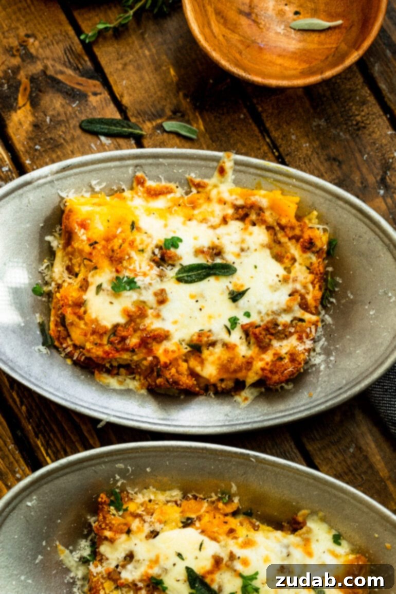 a photo of a large serving of butternut squash lasagna on a serving dish topped with melted cheese and fresh parsley and sage.