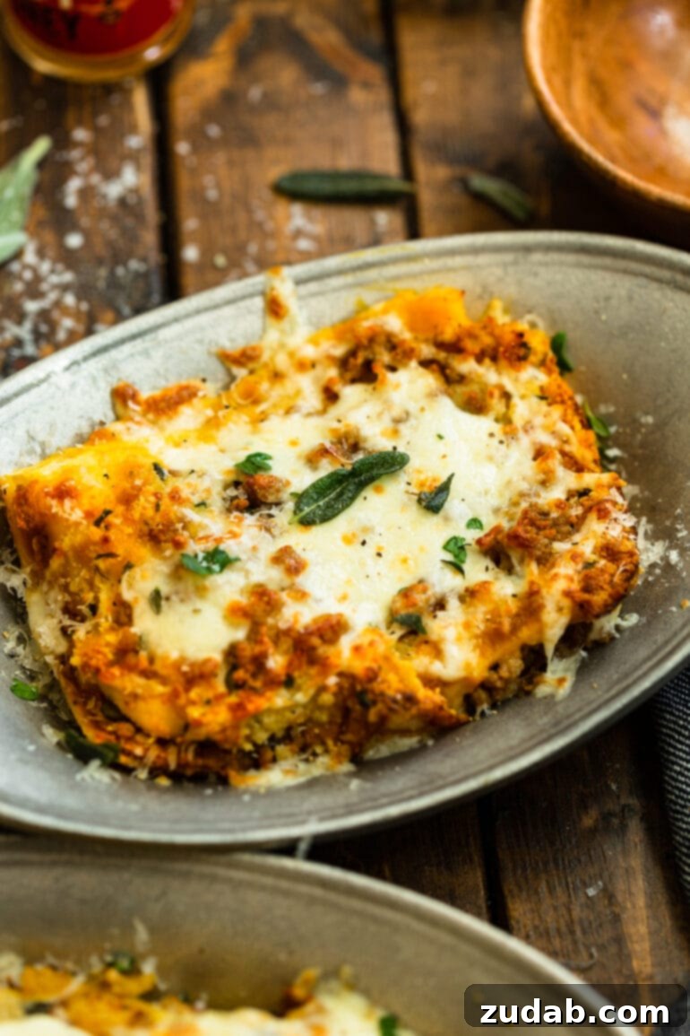 a photo of a large serving of butternut squash lasagna topped with melted cheese and fresh parsley and sage.