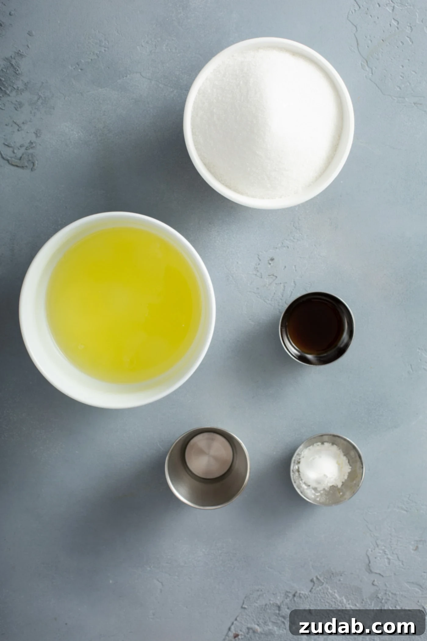 A tabletop with small containers of egg whites, sugar, corn starch, vanilla, and lemon juice.