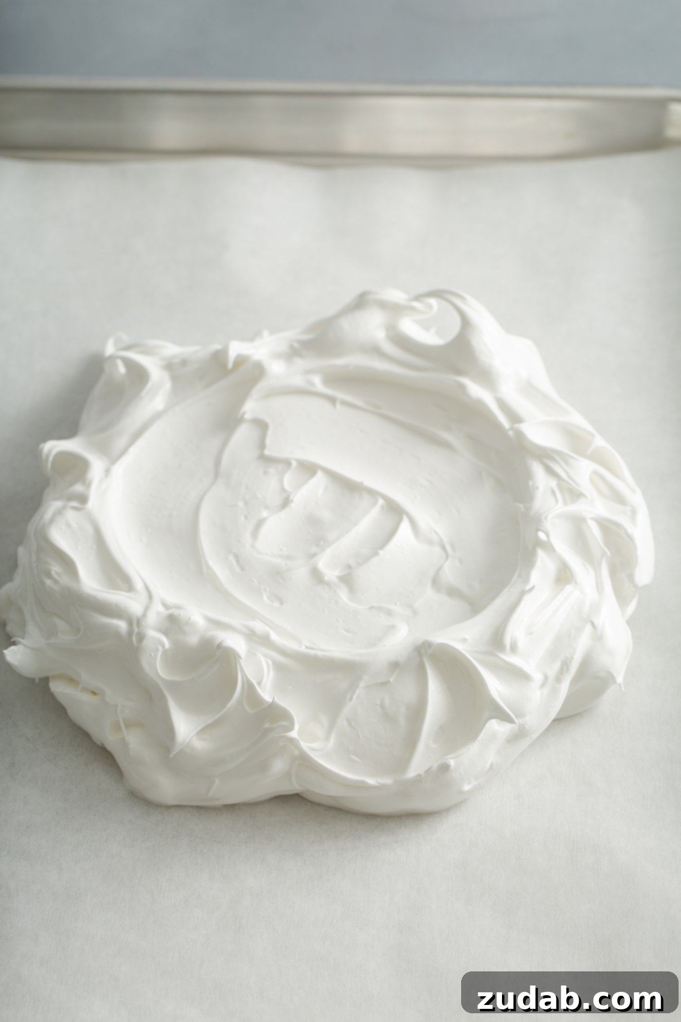Meringue that has been formed into a disk with a few fancy swirls and peaks.