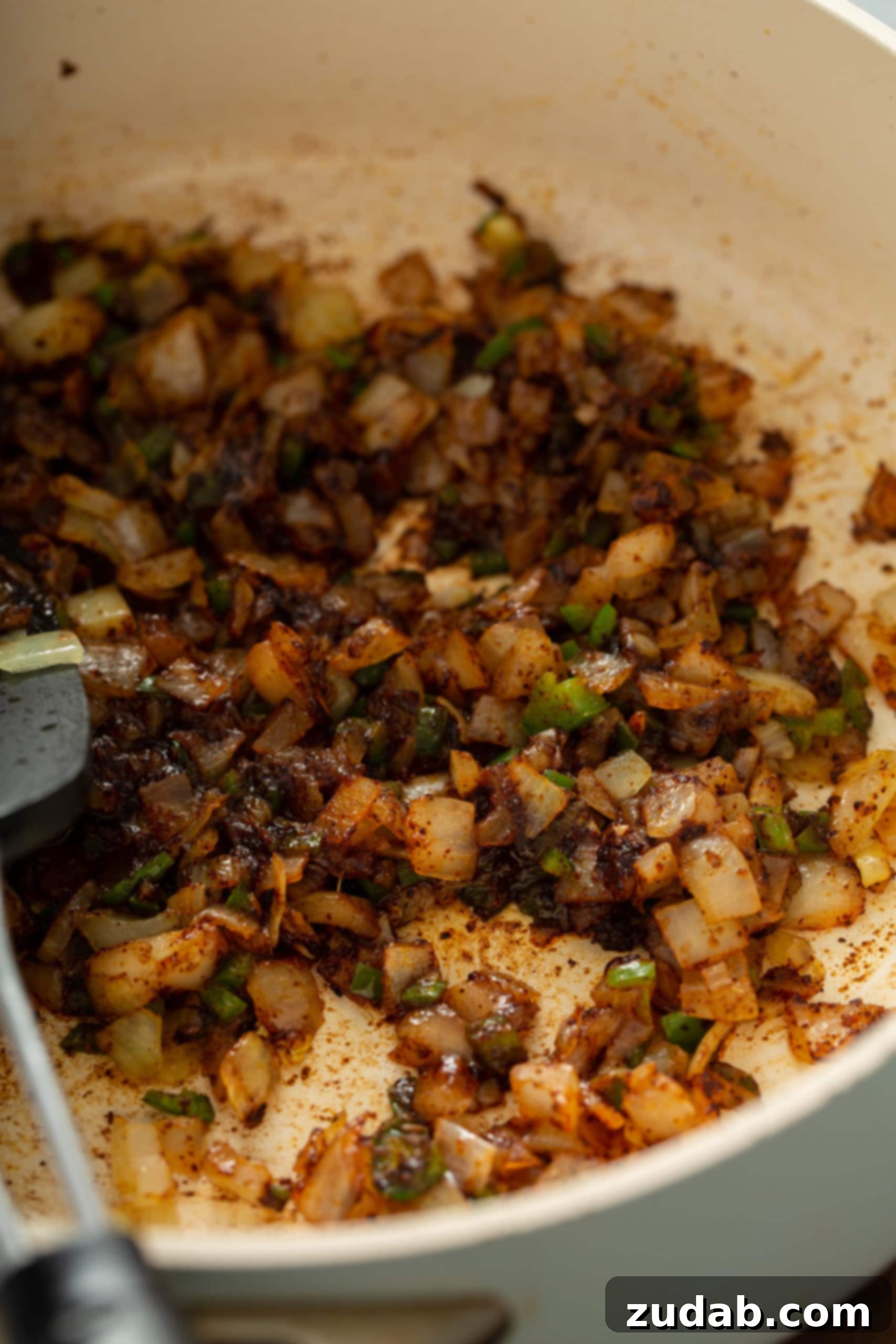 Homemade Red Enchilada Sauce A large skillet containing sautéed onions, finely diced jalapenos, and minced garlic, gently cooking over medium heat, forming the aromatic base for a delicious homemade red enchilada sauce.
