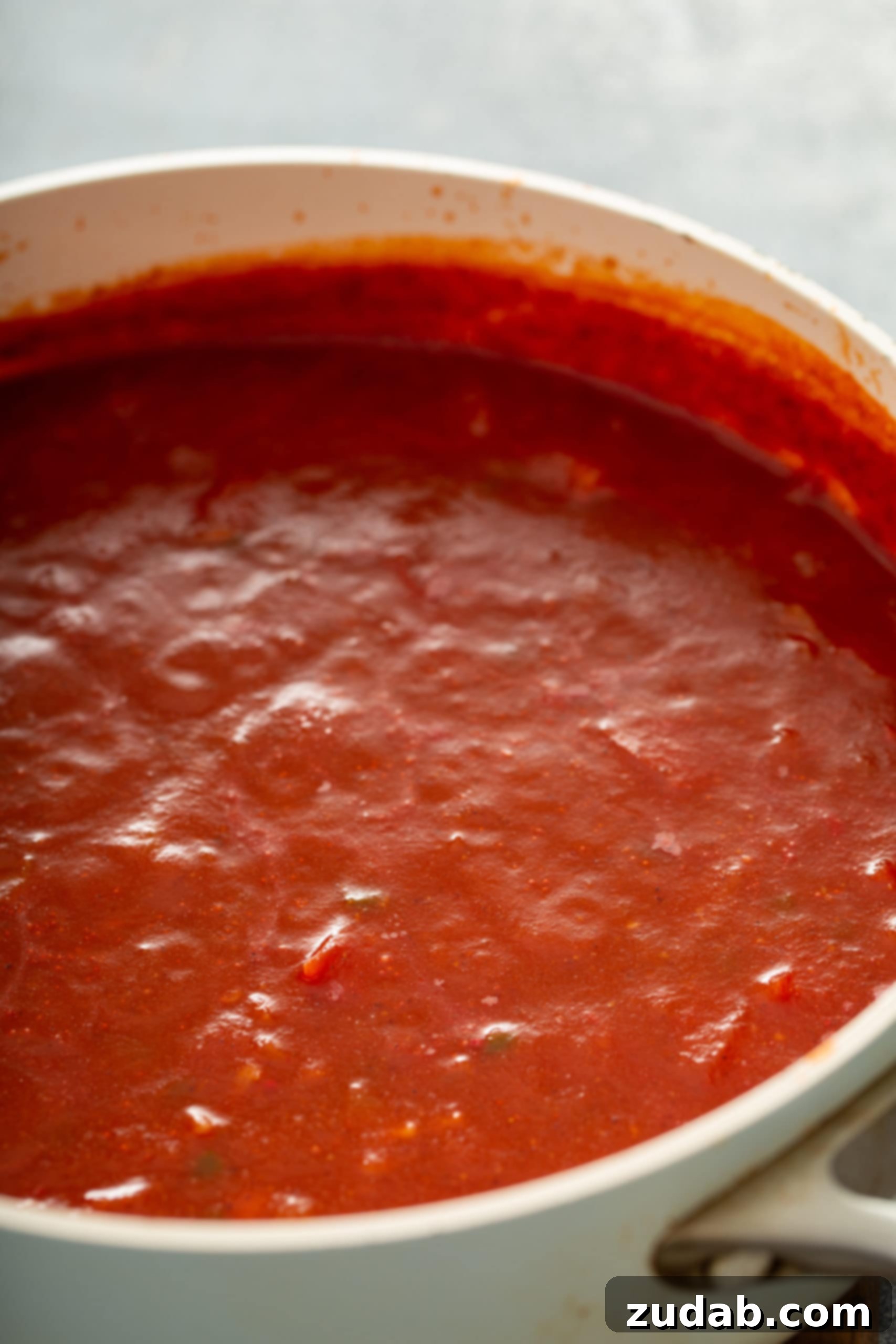 Homemade Red Enchilada Sauce A clear glass container filled with a perfectly smooth and vibrant homemade red enchilada sauce, ready to elevate any Mexican dish. The texture is rich and inviting.
