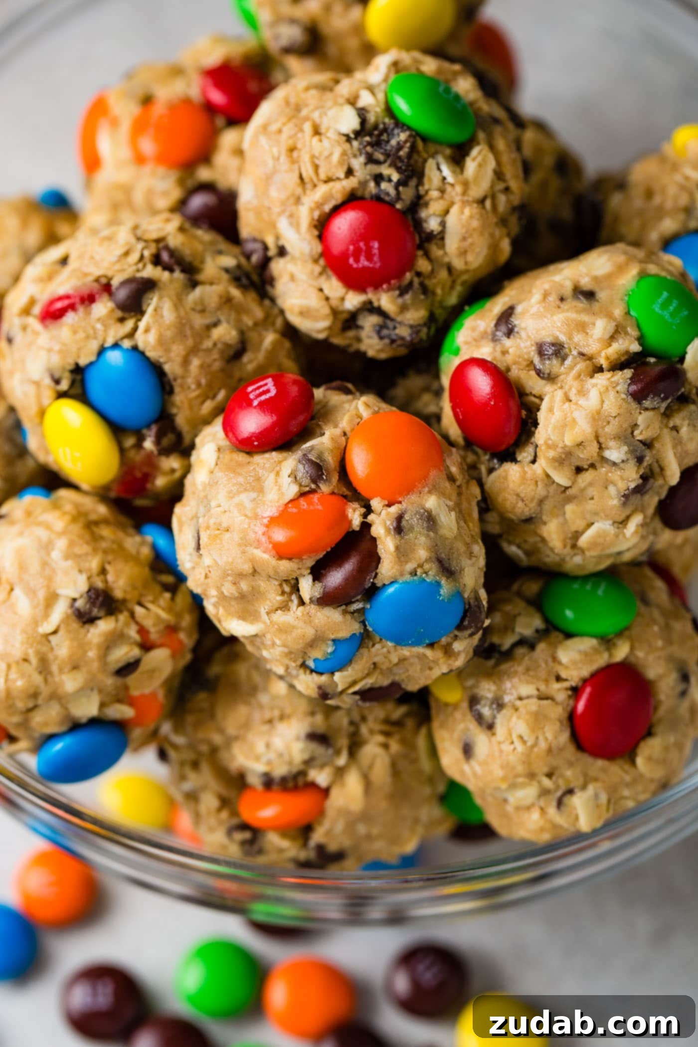 Loaded Peanut Butter Protein Bites 3 A bowl full of vibrant protein energy balls, featuring mini M&Ms, juicy raisins, and mini chocolate chips.