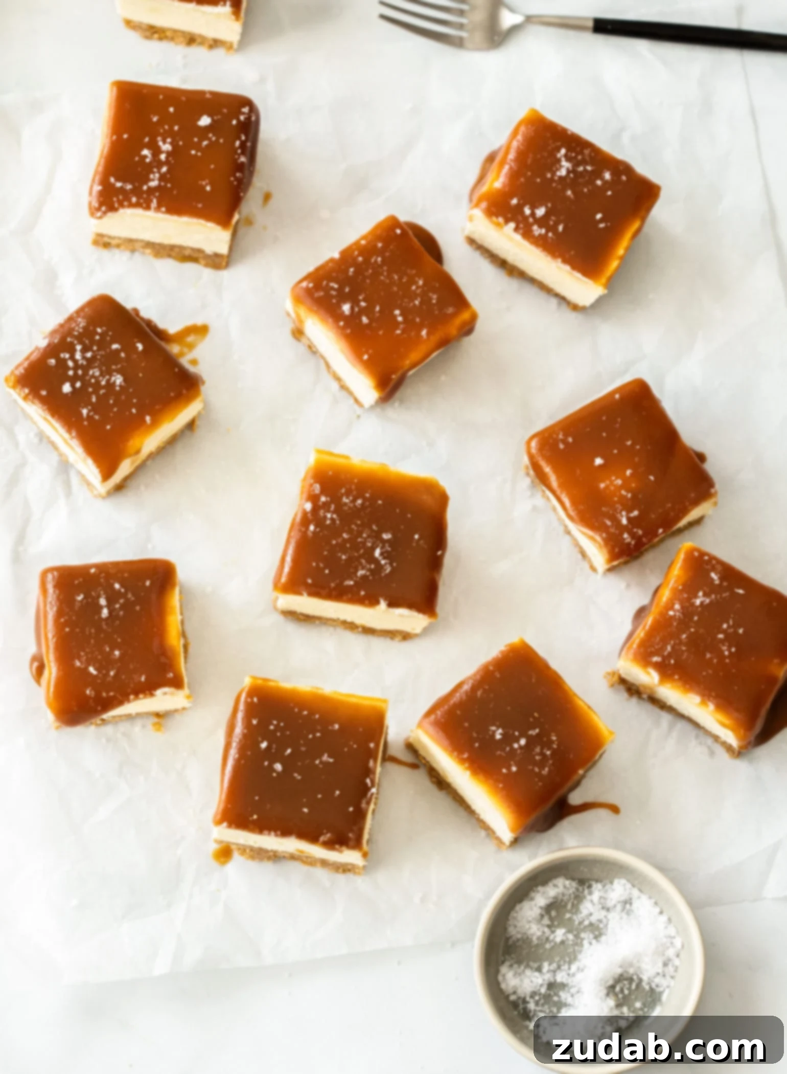 Effortless Caramel Bliss Bars 5 A full batch of 10 golden no-bake caramel cheesecake bars presented on white baking paper, ready to be served