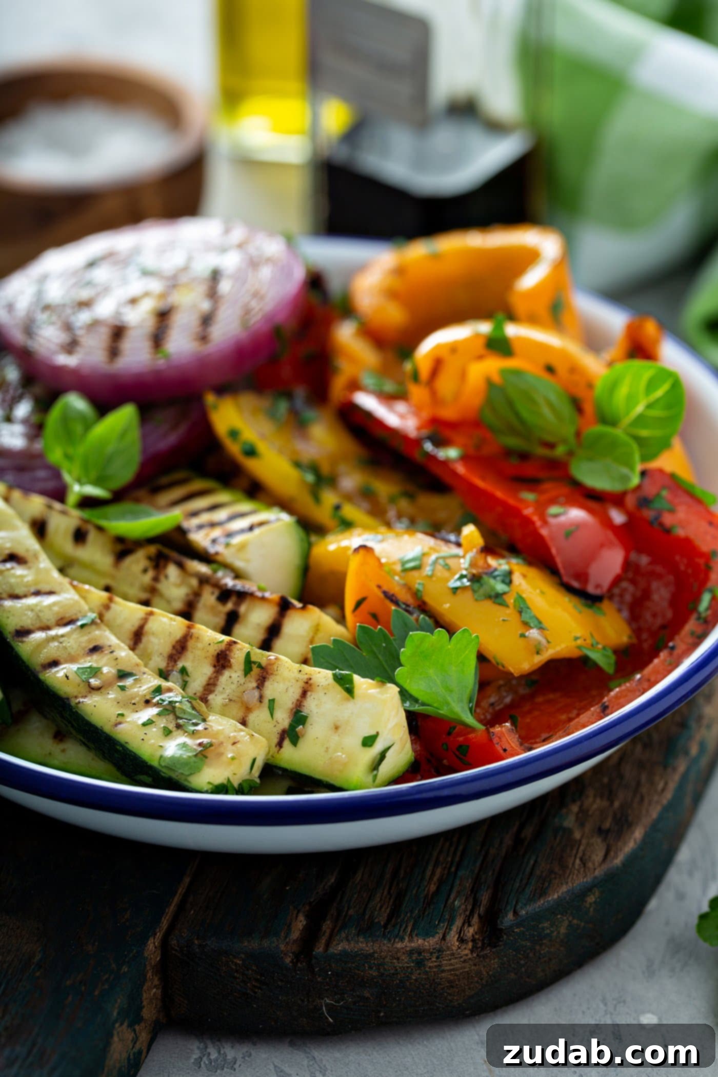 Grilled Vegetables with Balsamic Vinaigrette 12 A beautifully presented serving dish of grilled zucchini, red and yellow bell peppers, and red onions, all boasting golden grill marks and lightly sprinkled with fresh parsley leaves, creating an inviting and wholesome meal.