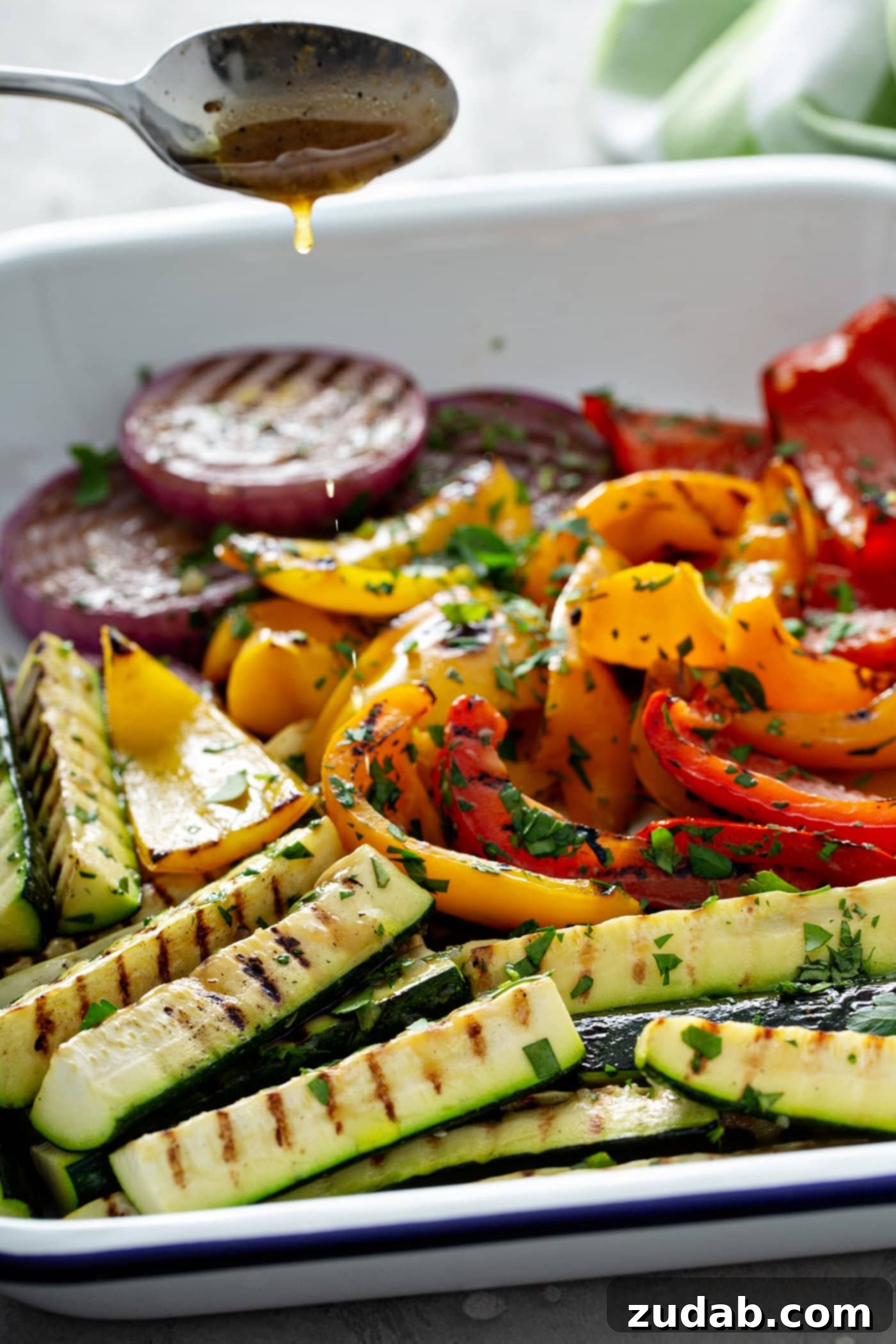 Grilled Vegetables with Balsamic Vinaigrette 9 A visually appealing serving dish brimming with perfectly grilled vegetables: tender sliced red onion, crisp zucchini wedges, and colorful red and yellow bell peppers, all boasting beautiful grill marks and garnished with fresh parsley leaves.