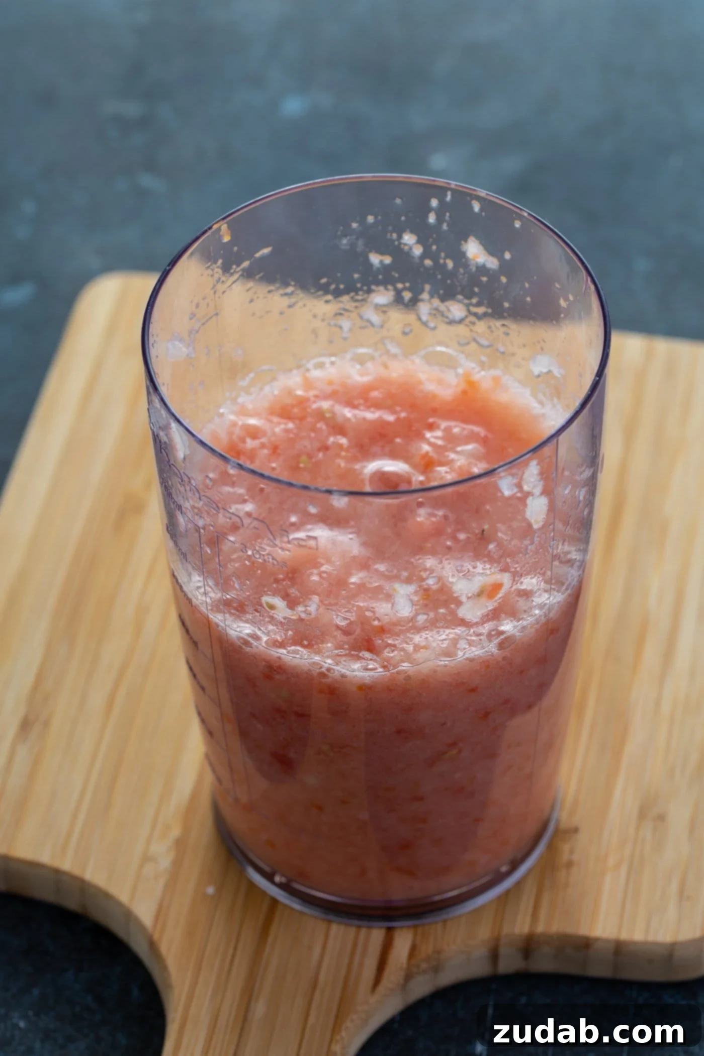 A glass containing blended tomatoes and onion.