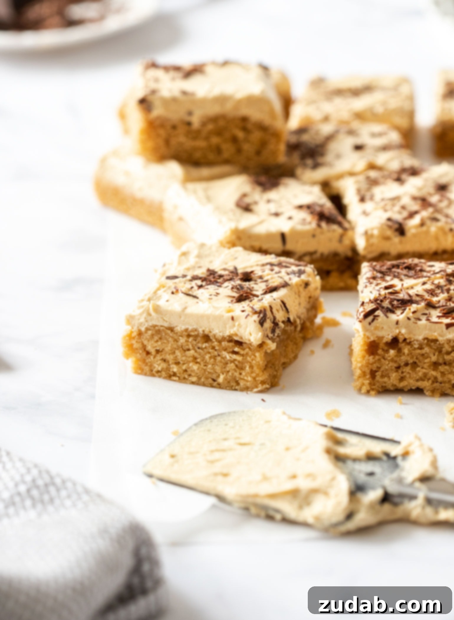 Ultimate Peanut Butter Sheet Cake 6 Several perfectly cut slices of rich peanut butter sheet cake are arranged neatly on a sheet of baking paper, highlighting the uniform layers and inviting presentation. Each slice is ready for serving.