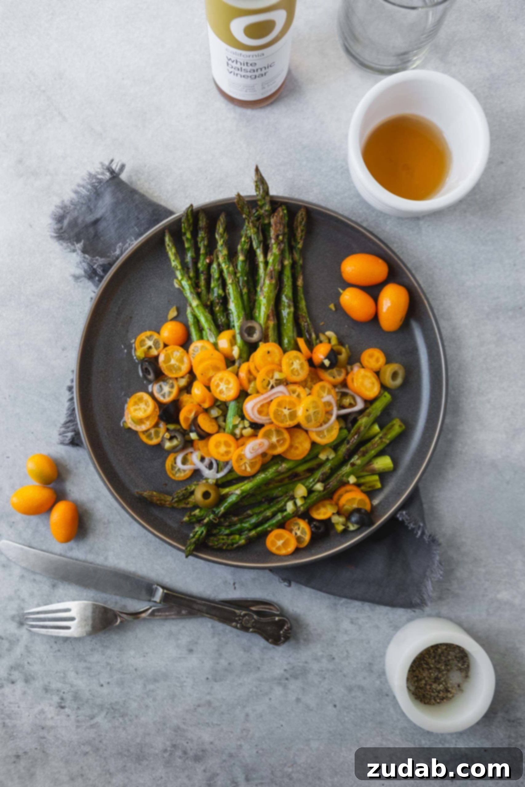A beautifully plated serving of roasted asparagus with bright kumquats and olives, ready to be enjoyed.