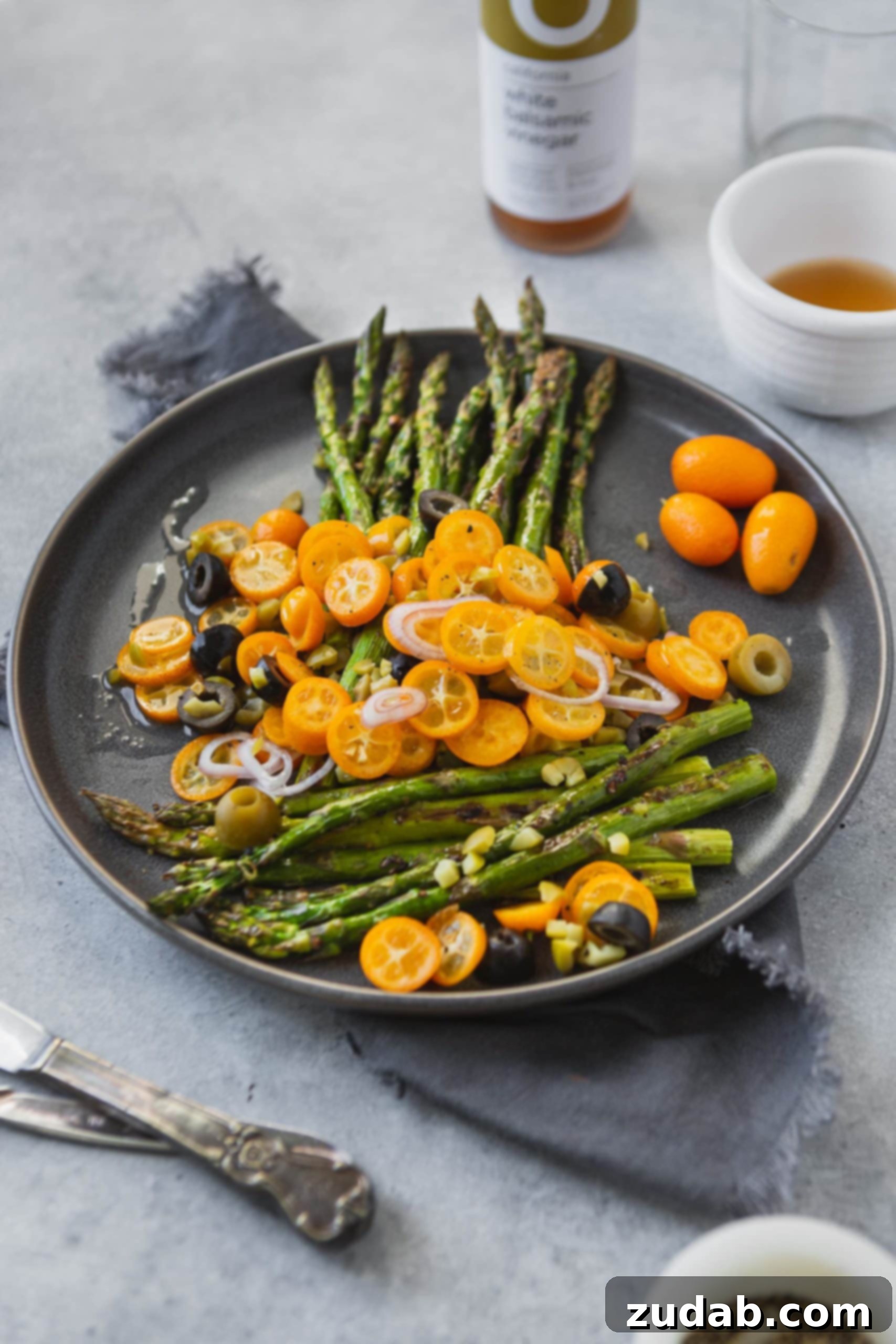 A beautifully composed flat lay of roasted asparagus with kumquats and olives, showcasing the dish's aesthetic appeal.