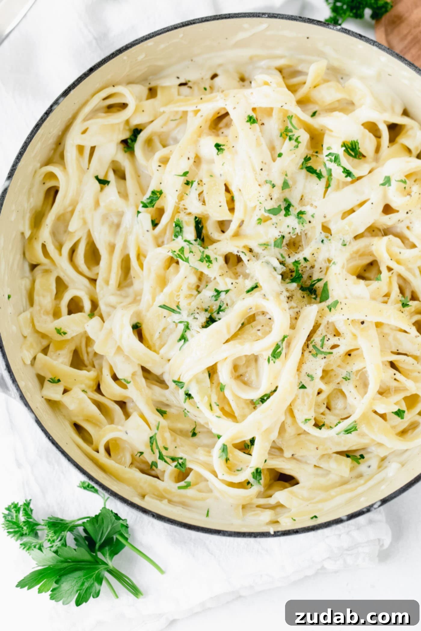 The Ultimate Velvety Alfredo Sauce 3 A large bowl of fettuccine alfredo, generously sprinkled with fresh parsley, ready to be served.