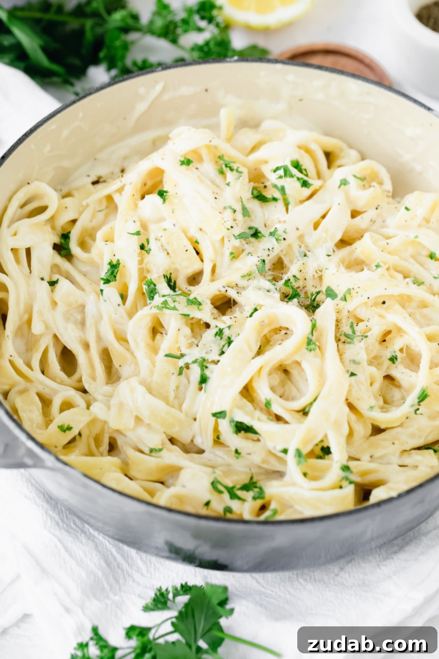 The Ultimate Velvety Alfredo Sauce 6 A generous serving of fettuccine alfredo, topped with fresh green parsley, presented in a large bowl.